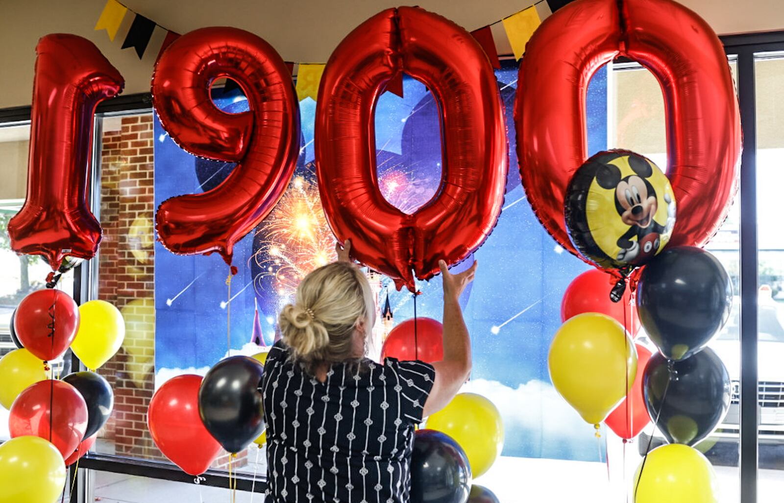 River Valley Credit Union employee Shauna Hickman straightens the balloons for the 1,900th wish of A Special Wish Foundation of Southwest Ohio, granted to the Fisher family of Moraine on Wednesday, Sept. 4, 2024. The family is planning for a trip to Walt Disney World in Florida. JIM NOELKER/STAFF