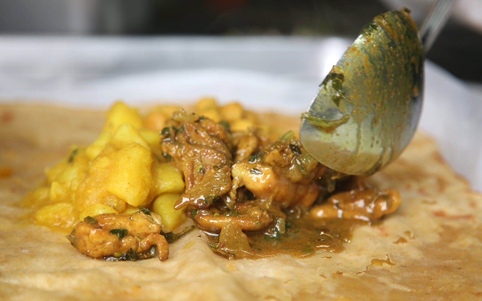 A combination of curried potatoes, chickpeas and a choice of chicken, beef or goat is combined inside roti, a flatbread with origins in Trinidad. This is one of the Caribbean dishes sold on the Soca food truck. LISA POWELL / STAFF