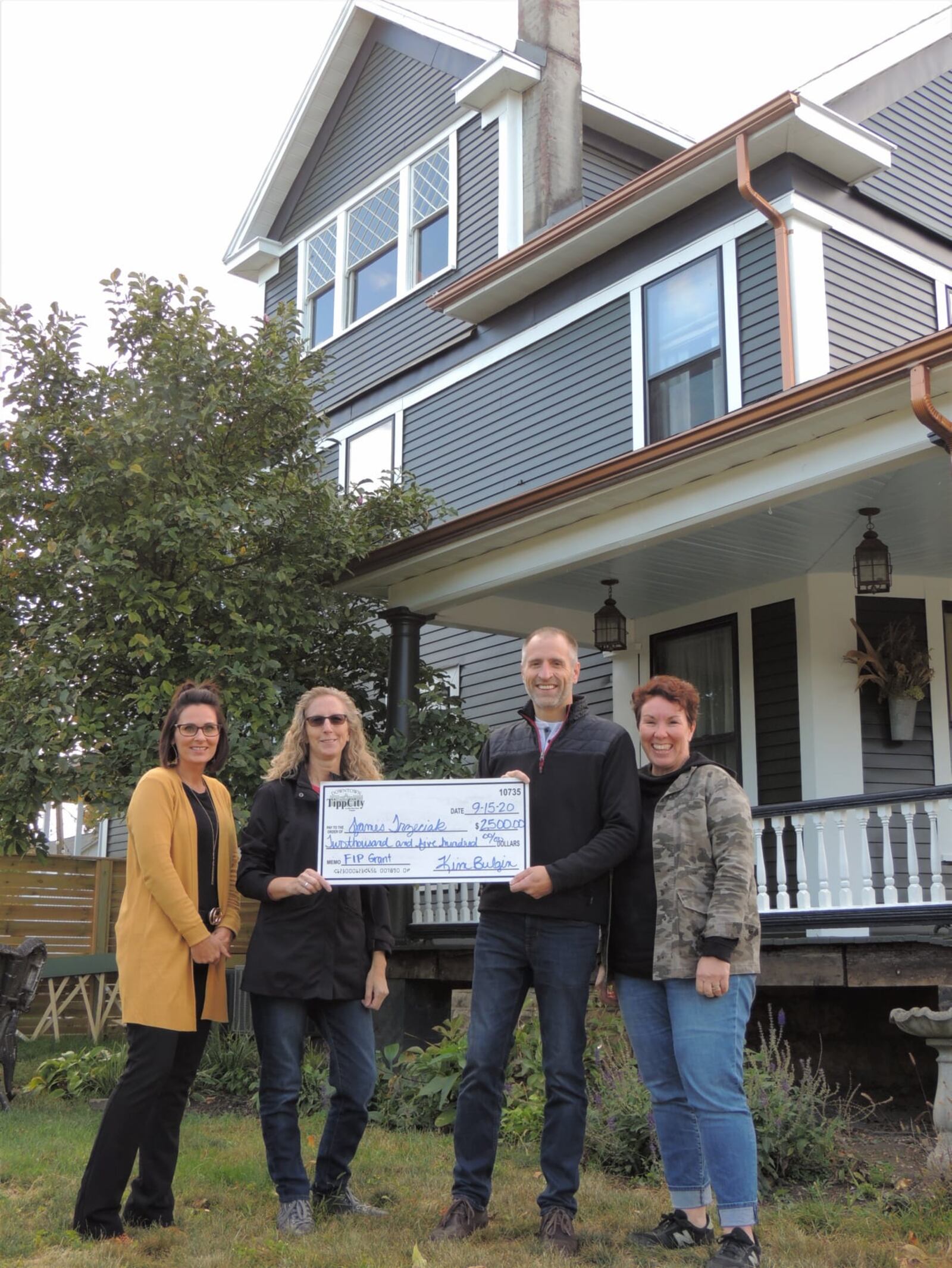 Kim Bulgin of the Downtown Tipp City Partnership posing with a check that is helping to preserve an historical area home.