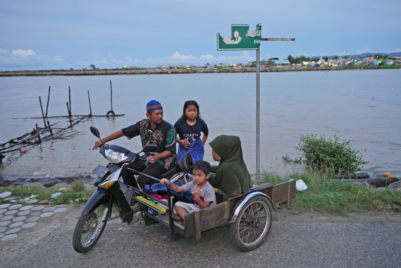 A family aride on a motorized tricycle on Ulee Lheue beach, one of the ares hardest hit by the Indian Ocean tsunami in 2004, in Banda Aceh, Indonesia, Friday, Dec. 13, 2024. (AP Photo/Achmad Ibrahim)