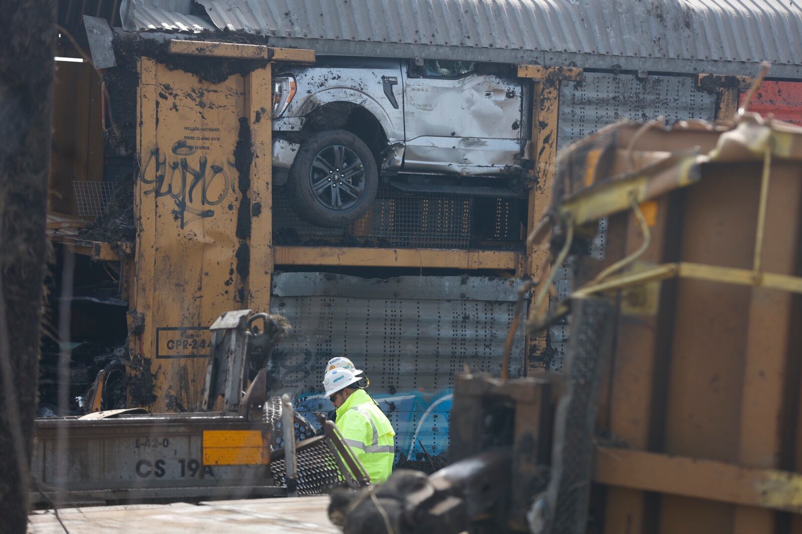 Work continues on cleanup of the train derailment in Clark County Monday, March 6, 2023. A worker is shown in the foreground as a load of Ford F-150 trucks is shown in the background. BILL LACKEY/STAFF