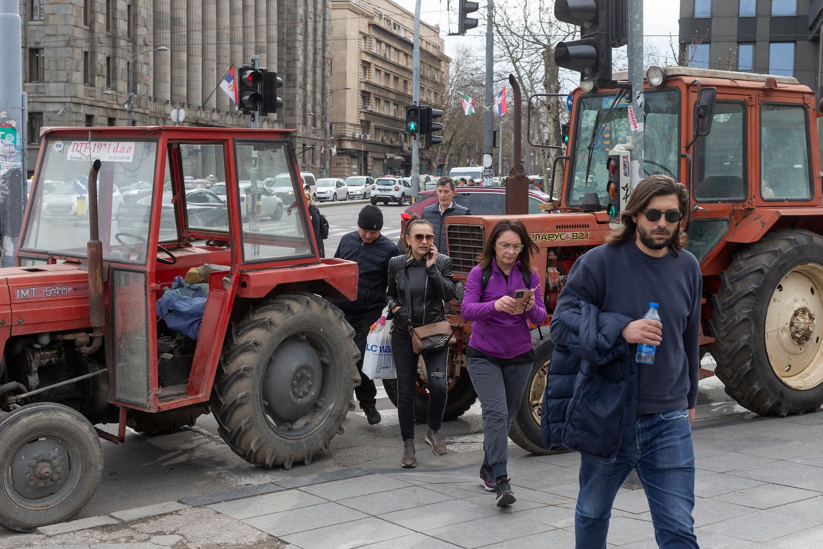 People walk past tractors brought in and parked by supporters of the Serbian president Aleksandar Vucic in Belgrade, Serbia, Friday, March 14, 2025, as the country prepares for a major anti-corruption rally this weekend. (AP Photo/Marko Drobnjakovic)