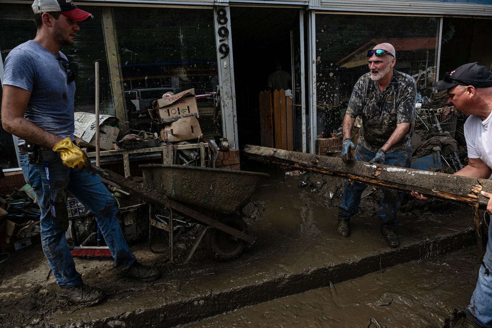 People remove debris from a storefront damaged by flooding in Fleming-Neon, Ky., Aug. 2, 2022. The region, one of the poorest in the country, is full of modest, unprotected homes and decaying infrastructure. Some residents say they won’t return. (Jon Cherry/The New York Times)