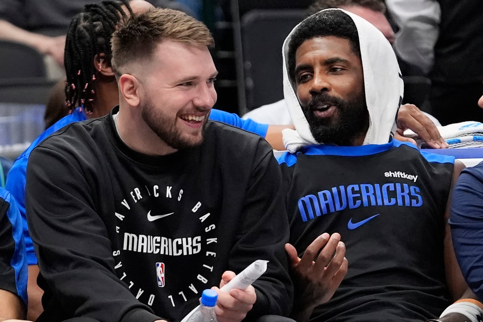 Sitting on the bench Dallas Mavericks guard Luka Doncic, left, shares a laugh with teammate fellow guard Kyrie Irving during a preseason NBA basketball game against the Milwaukee Bucks Thursday, Oct. 17, 2024, in Dallas. (AP Photo/LM Otero)