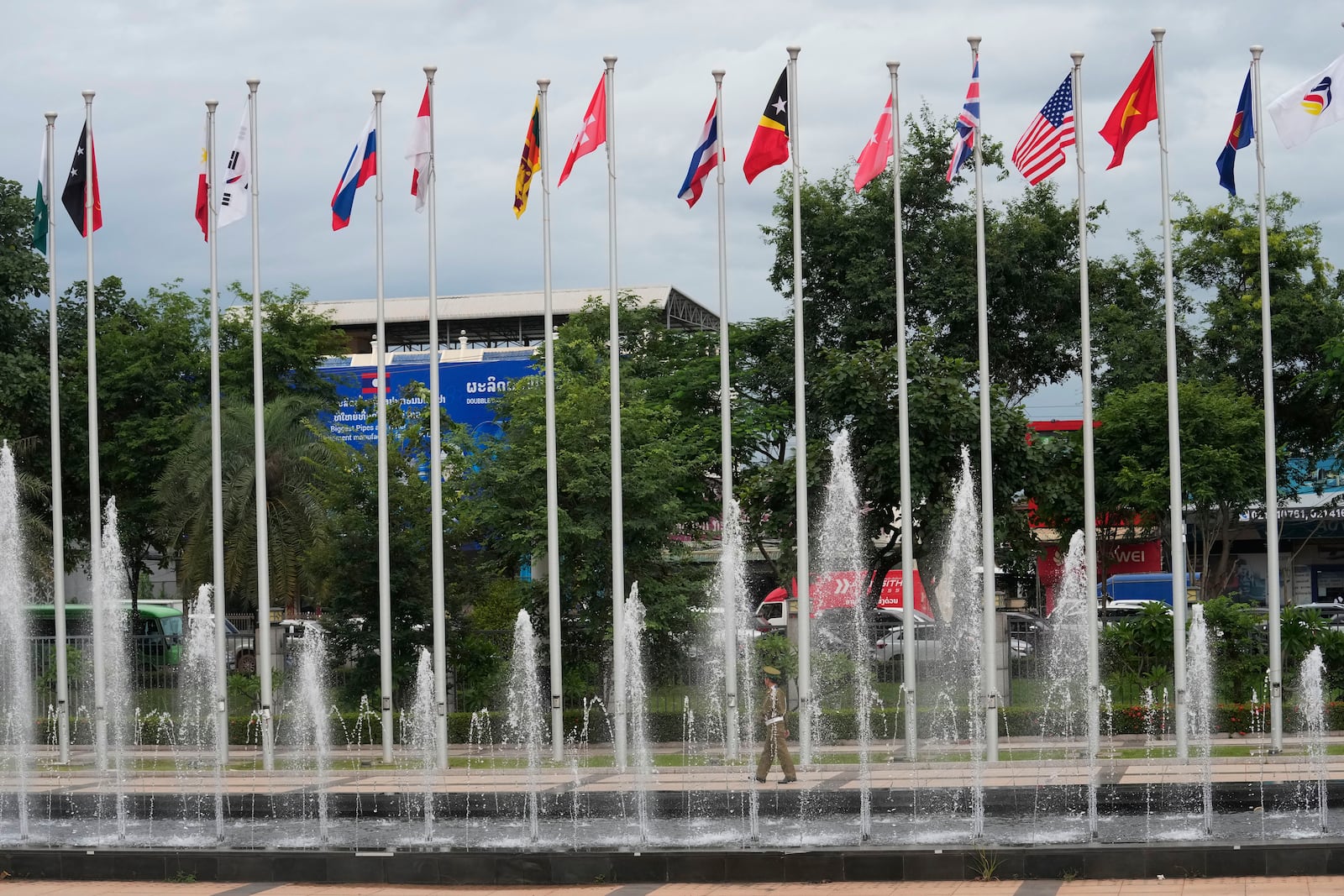 FILE- A police officer walks along flags of nations participating in the meetings of the Association of Southeast Asian Nations (ASEAN) at the national convention center in Vientiane, Laos, Wednesday, July 24, 2024. (AP Photo/Sakchai Lalit, File)