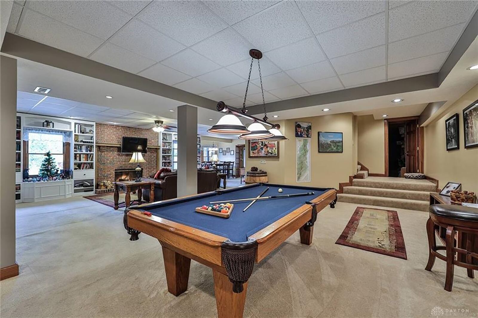 Downstairs, the space has been divided into a recreation room, a family room, a game room and a full kitchen area. A brick, wood-burning fireplace is flanked by built-in bookcases that surround the daylight windows. CONTRIBUTED PHOTO