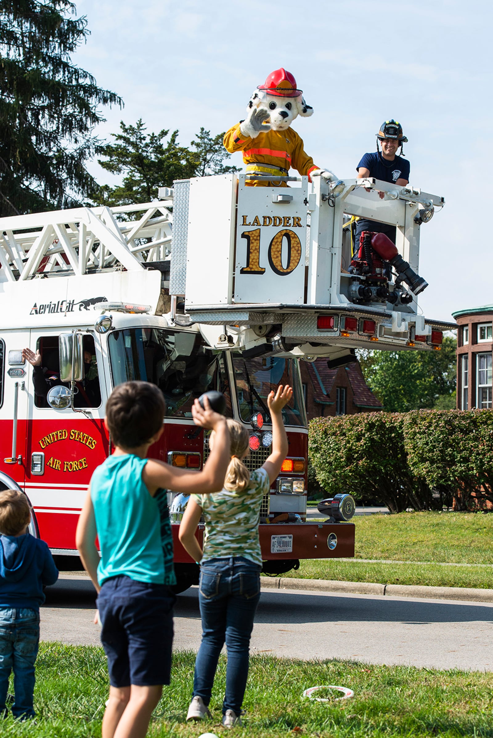 Sparky the Fire Dog and members of the 788th Civil Engineer Squadron Fire Department wave to children in the Brick Quarters housing area during a parade Oct. 2 to kick off Fire Prevention Week at Wright-Patterson Air Force Base. U.S. AIR FORCE PHOTO/WESLEY FARNSWORTH