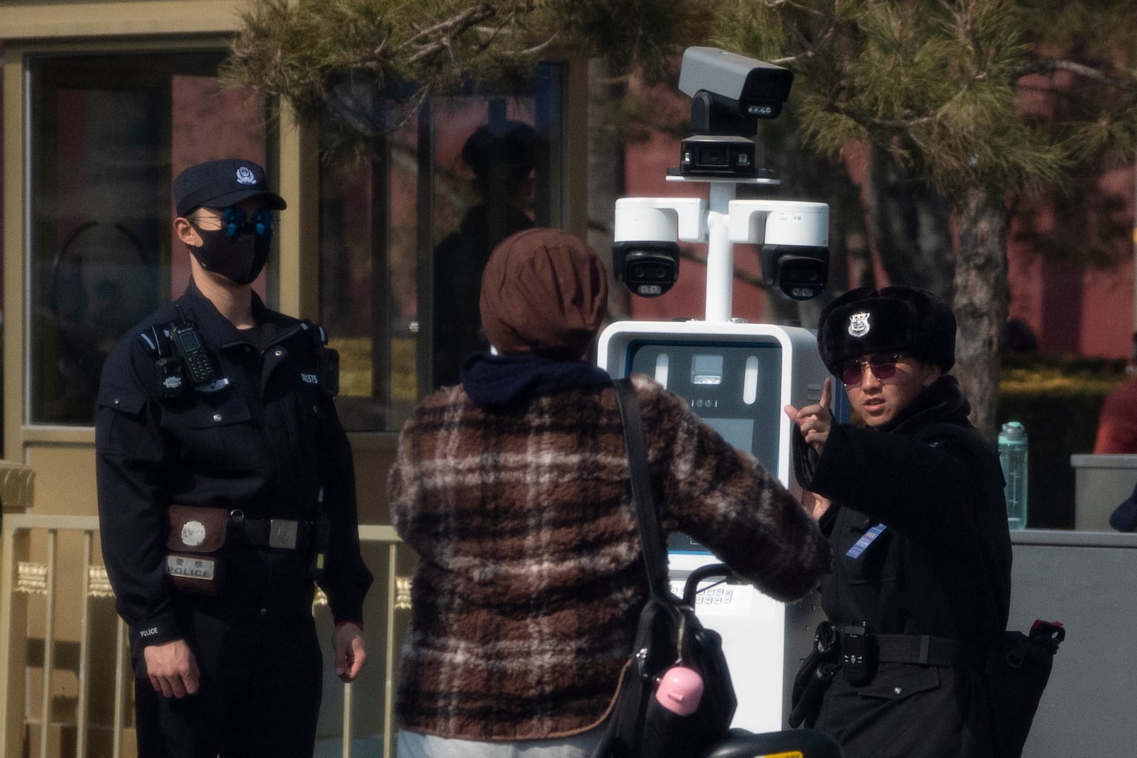 A Chinese security person checks the identities of cyclists passing near the Great Hall of the People ahead of the National People's Congress in Beijing, on Feb. 28, 2025. (AP Photo/Ng Han Guan)