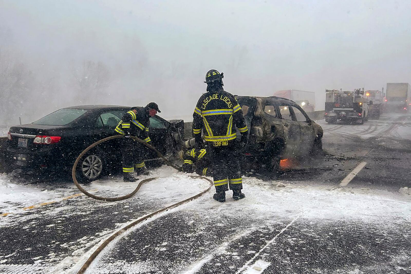 In this image provided by the Multnomah County Sheriff's Office officials respond after a vehicle caught fire on westbound Interstate 84 on Thursday, Feb. 13, 2025, near Multnomah Falls, Ore. (Multnomah County Sheriff's Office via AP)