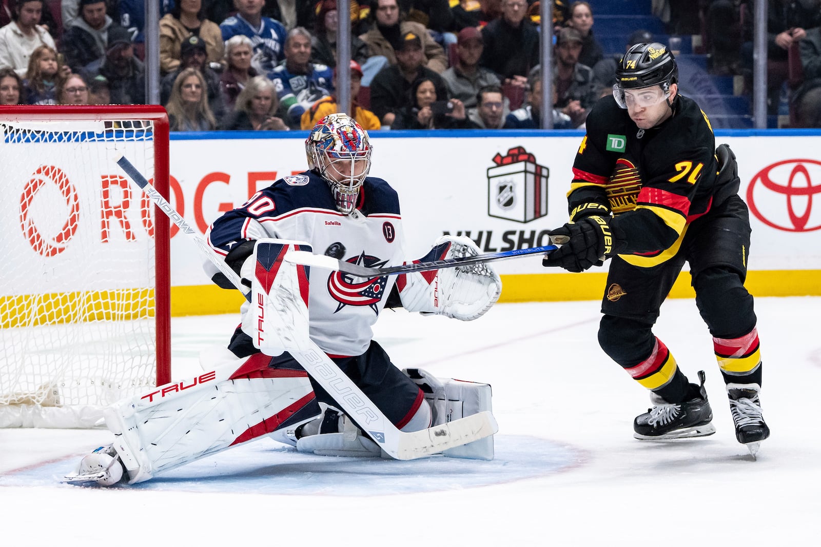 Columbus Blue Jackets goaltender Elvis Merzlikins (90) stops Vancouver Canucks' Jake DeBrusk (74) during the third period of an NHL hockey game in Vancouver, British Columbia, Friday, Dec. 6, 2024. (Ethan Cairns/The Canadian Press via AP)