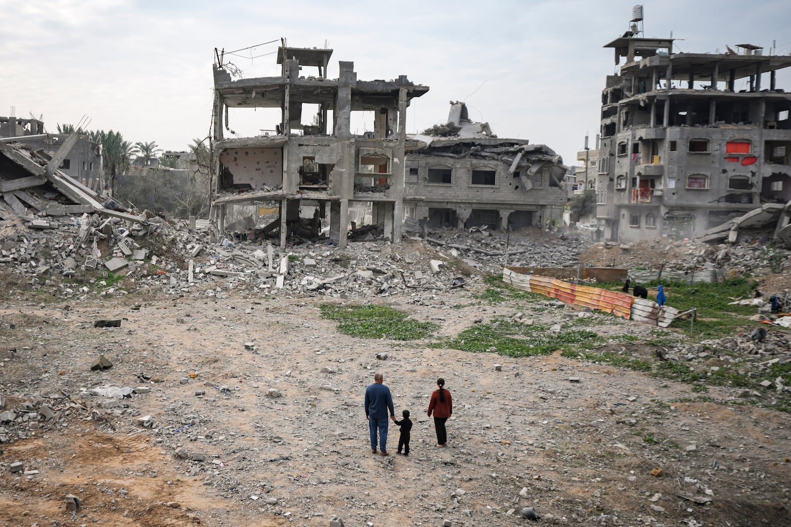 Palestinians look at their destroyed home, in Bureij, central Gaza Strip, Wednesday, Jan. 22, 2025, days after the ceasefire deal between Israel and Hamas came into effect. (AP Photo/Abdel Kareem Hana)