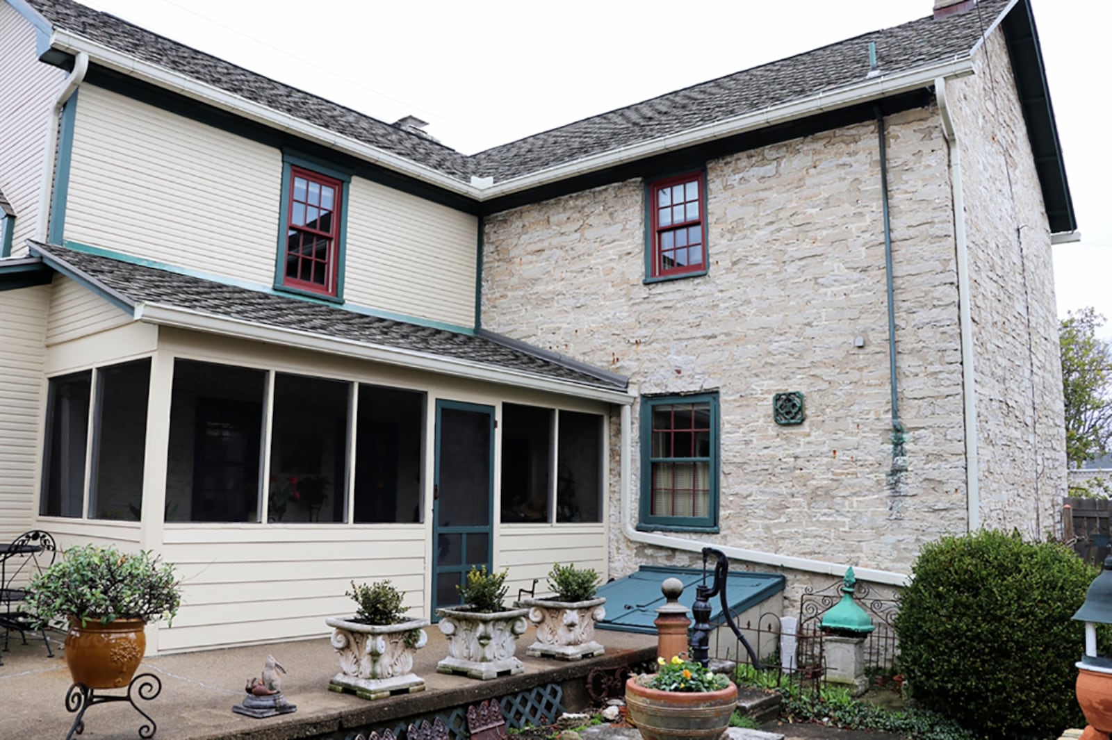 While the formal entry is centered from a stone walkway from the city sidewalk, the causal entrance is through a gate into the terrace stone patio courtyard to the screen-enclosed porch. The courtyard has an original well pump, cellar doors, and a stone wall that frames garden beds. CONTRIBUTED PHOTO BY KATHY TYLER