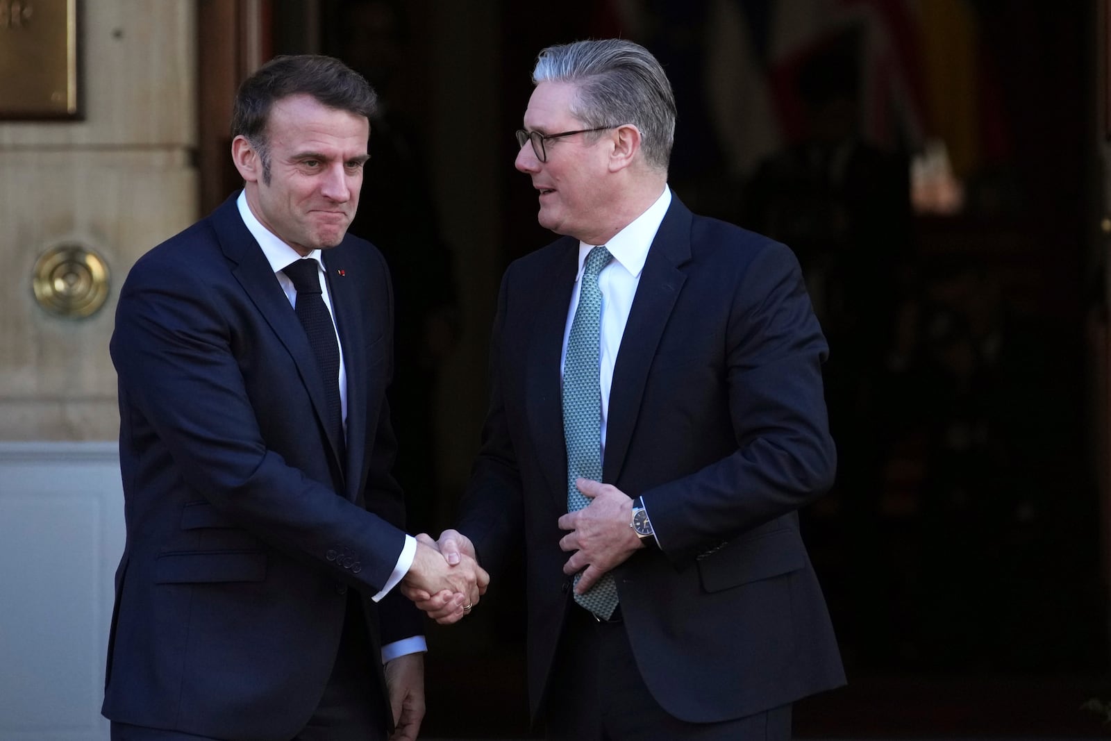 Britain's Prime Minister Keir Starmer, right, greets French President Emmanuel Macron as he arrives for a summit on Ukraine at Lancaster House in London, Sunday, March 2, 2025. (AP Photo/Christophe Ena, Pool)