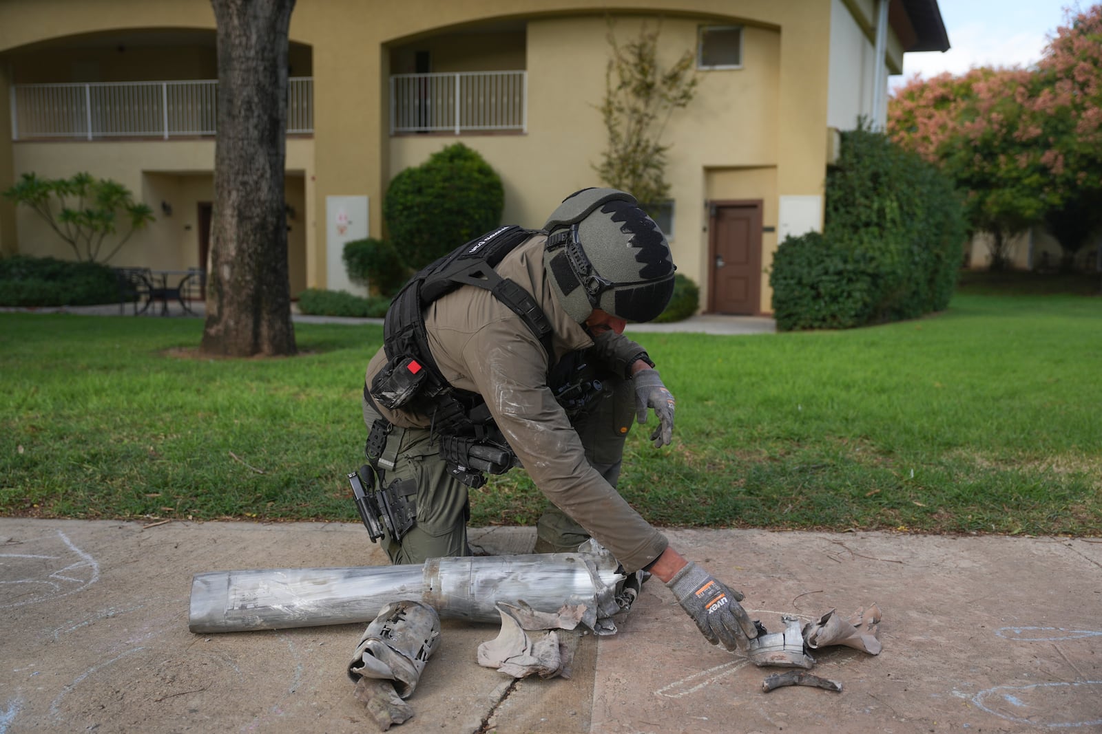 An Israeli bomb squad policeman collects the pieces of a rocket that was fired from Lebanon in Kibbutz Kfar Blum, northern Israel Sunday Nov. 24, 2024. (AP Photo/Ohad Zwigenberg)