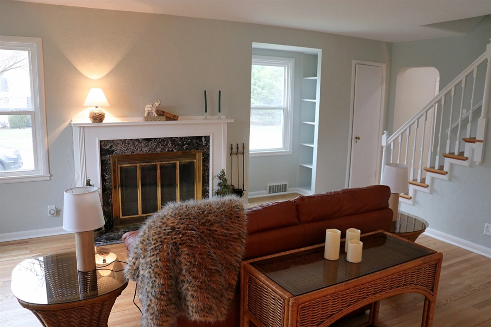 A wood-burning fireplace has black marble surround and hearth and a wood mantel. Next to the fireplace is a window niche with built-in shelves, creating a sunny reading area.