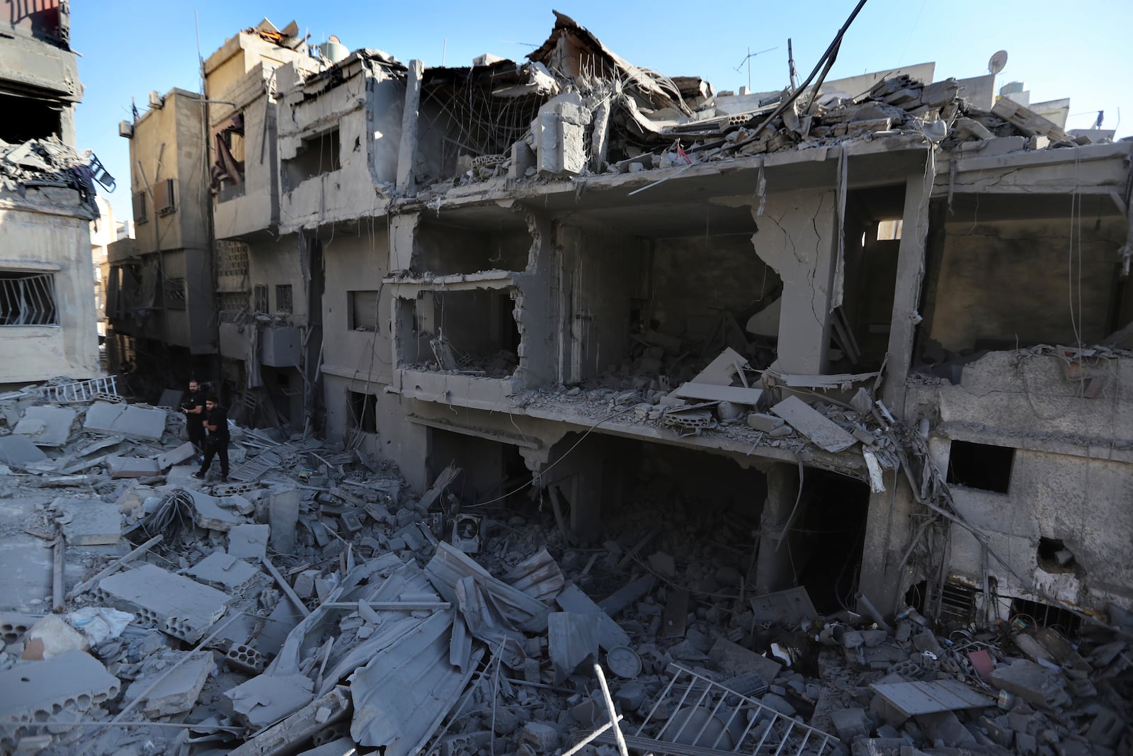 People observe buildings destroyed by Israeli airstrikes, in Tyre, Lebanon, Wednesday, Oct. 23, 2024. (AP Photo/Mohammed Zaatari)