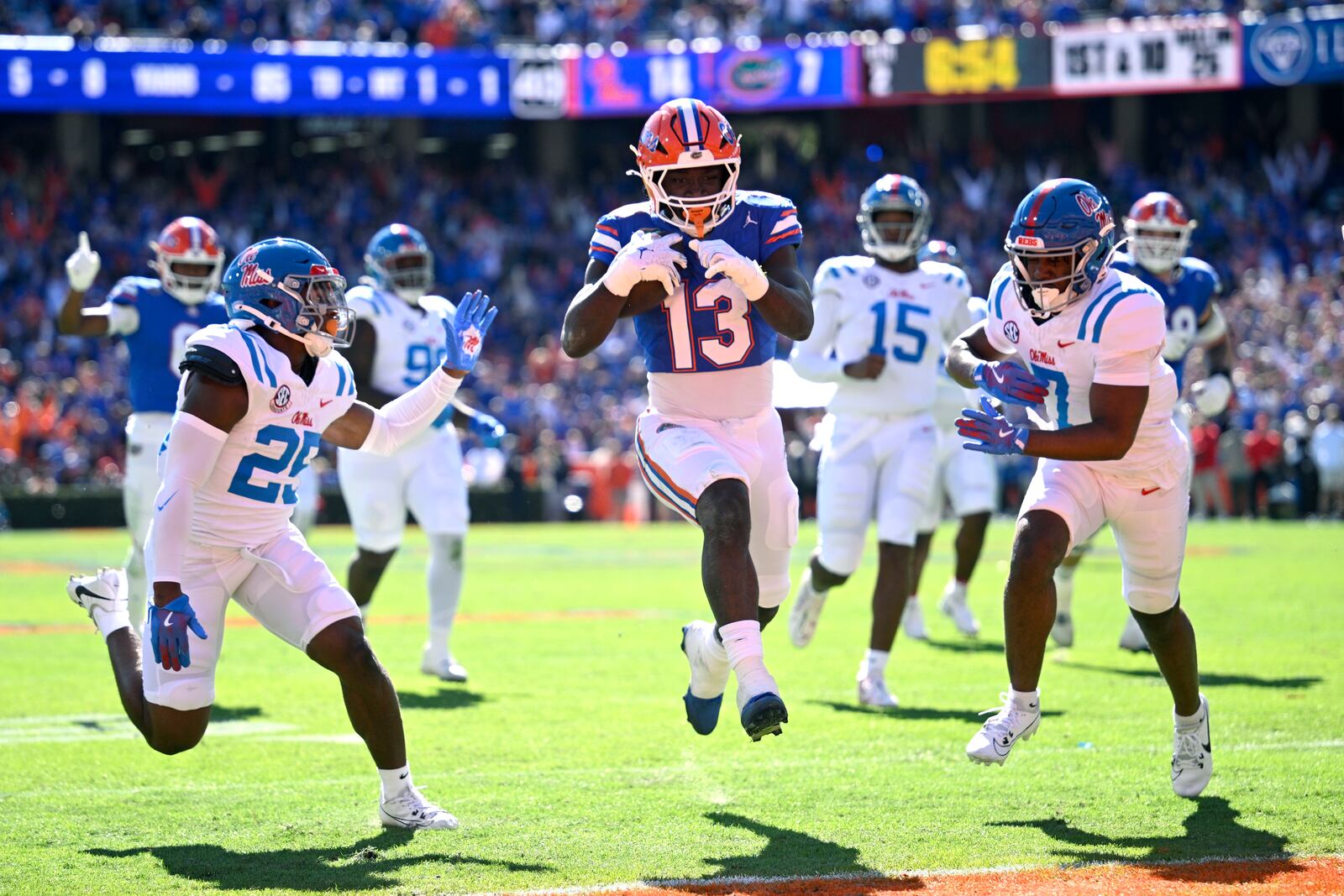 Florida running back Jadan Baugh (13) scores a touchdown between Mississippi safety Trey Washington (25) and safety Louis Moore (7) on a 25-yard pass play during the first half of an NCAA college football game, Saturday, Nov. 23, 2024, in Gainesville, Fla. (AP Photo/Phelan M. Ebenhack)