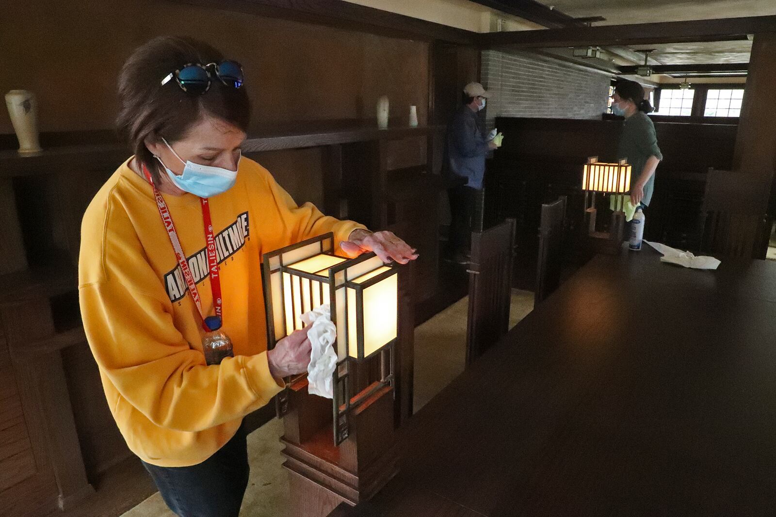 Kate Archdeacon, from Dayton, one of the volunteers cleaning and getting the Westcott House ready to reopen for tours on Saturday, cleans the lamps on each corner of the dinning room table in the Springfield house that was built by Frank Lloyd Wright. BILL LACKEY/STAFF