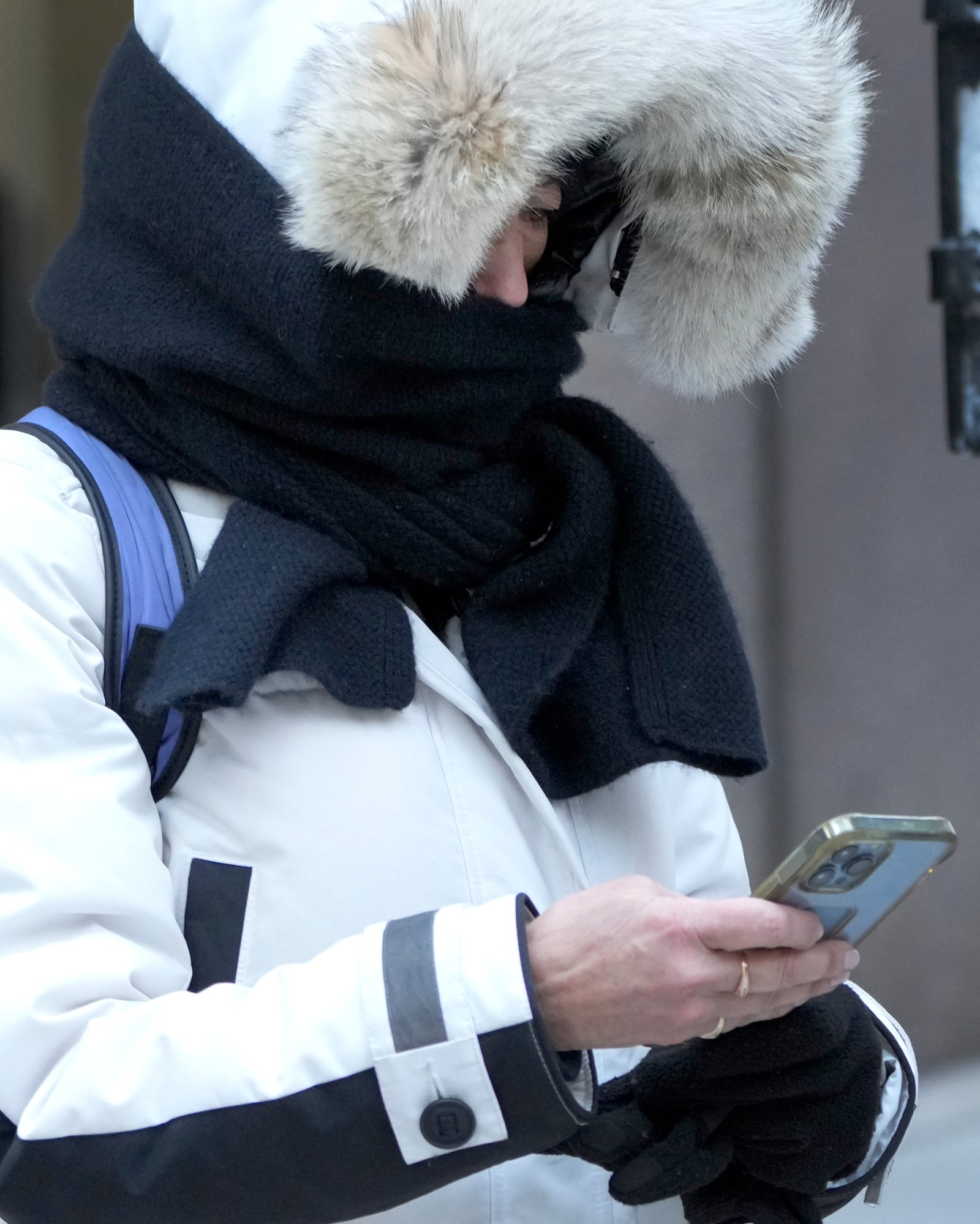 A woman checks her cellphone as an Arctic blast brings single-digit temperatures with wind chills below zero on Thursday, Dec. 12, 2024, in Chicago. (AP Photo/Charles Rex Arbogast)