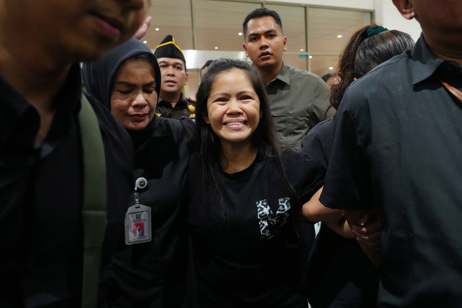 Mary Jane Veloso, center, a Filipina who was on death row in Indonesia and was nearly executed by firing squad in 2015, smiles as she arrives at Soekarno-Hatta International Airport for her repatriation to the Philippines, in Tangerang, Indonesia, Tuesday, Dec. 17, 2024. (AP Photo/Tatan Syuflana)