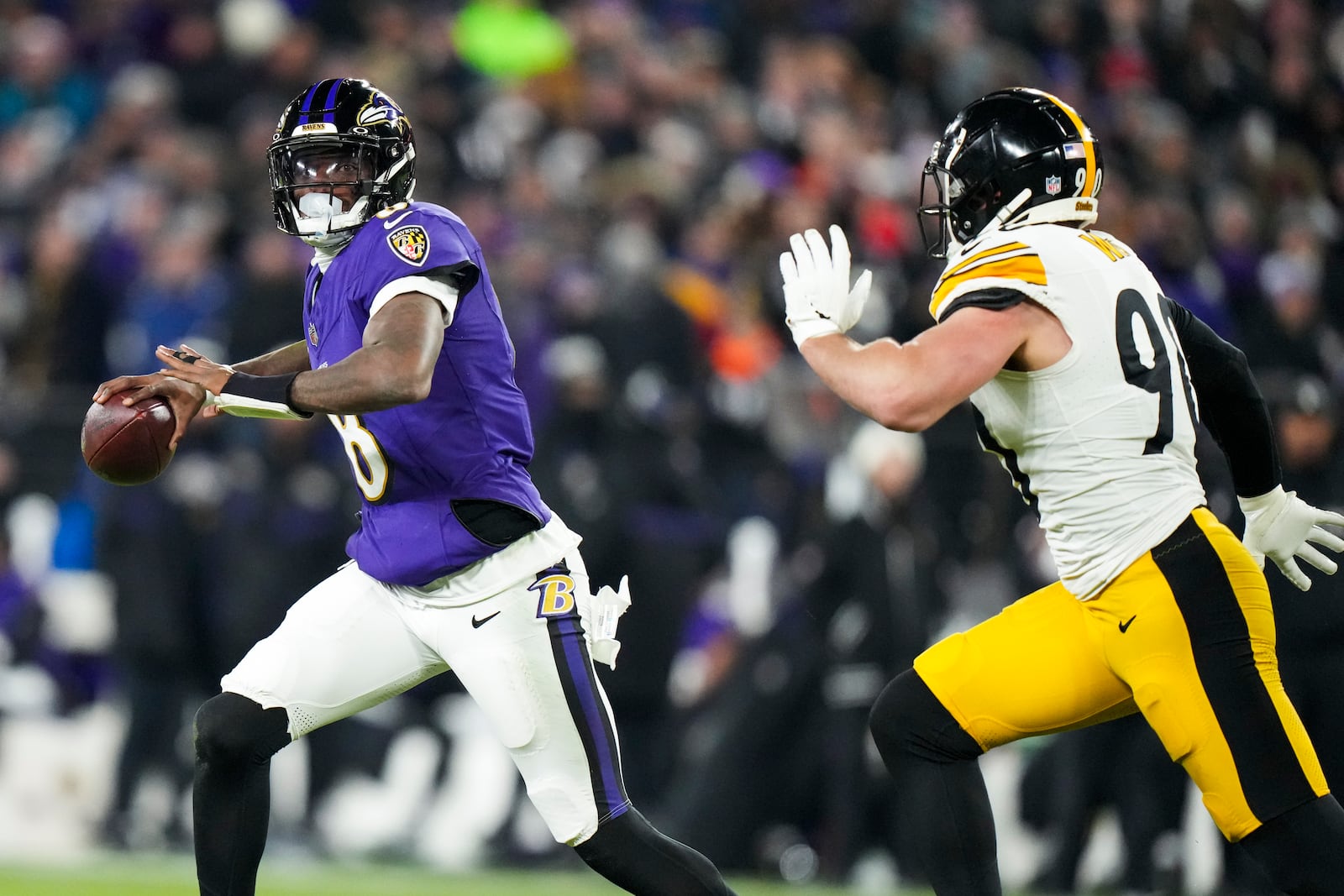 Baltimore Ravens quarterback Lamar Jackson, left, looks to pass as Pittsburgh Steelers linebacker T.J. Watt applies pressure during the first half of an NFL wild-card playoff football game, Saturday, Jan. 11, 2025, in Baltimore. (AP Photo/Stephanie Scarbrough)