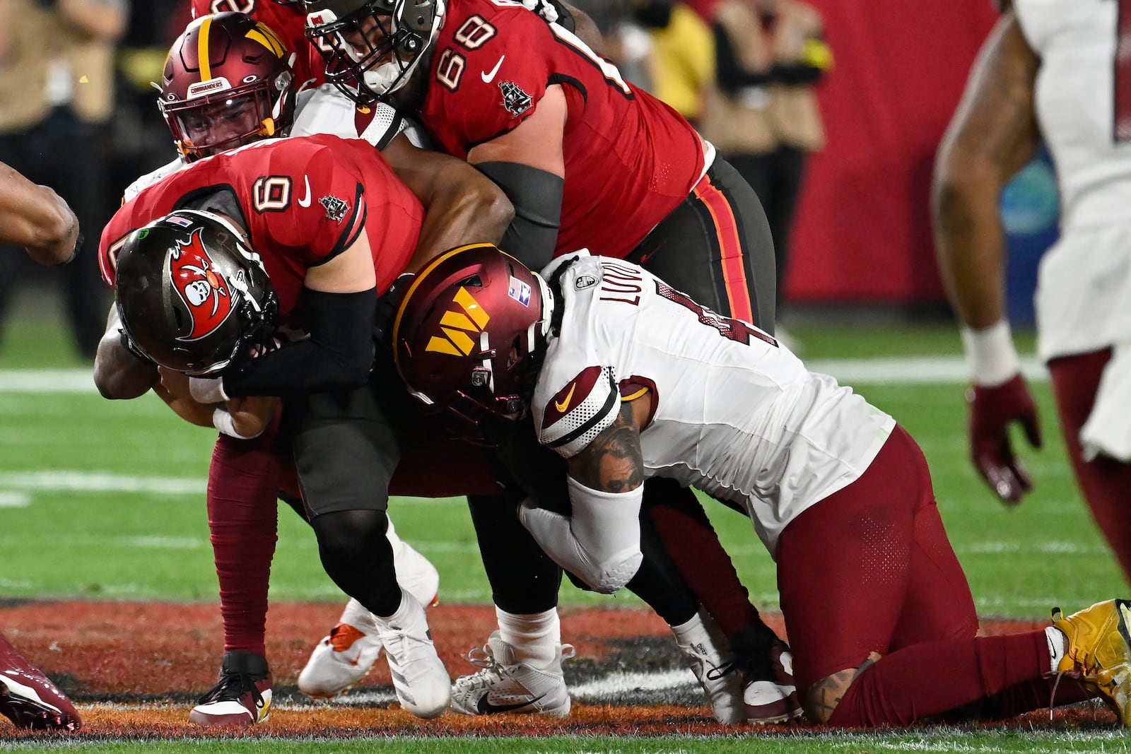 Tampa Bay Buccaneers quarterback Baker Mayfield (6) is tackled by Washington Commanders linebacker Frankie Luvu, right, and defensive end Dorance Armstrong during the first half of an NFL wild-card playoff football game in Tampa, Fla., Sunday, Jan. 12, 2025. (AP Photo/Jason Behnken)