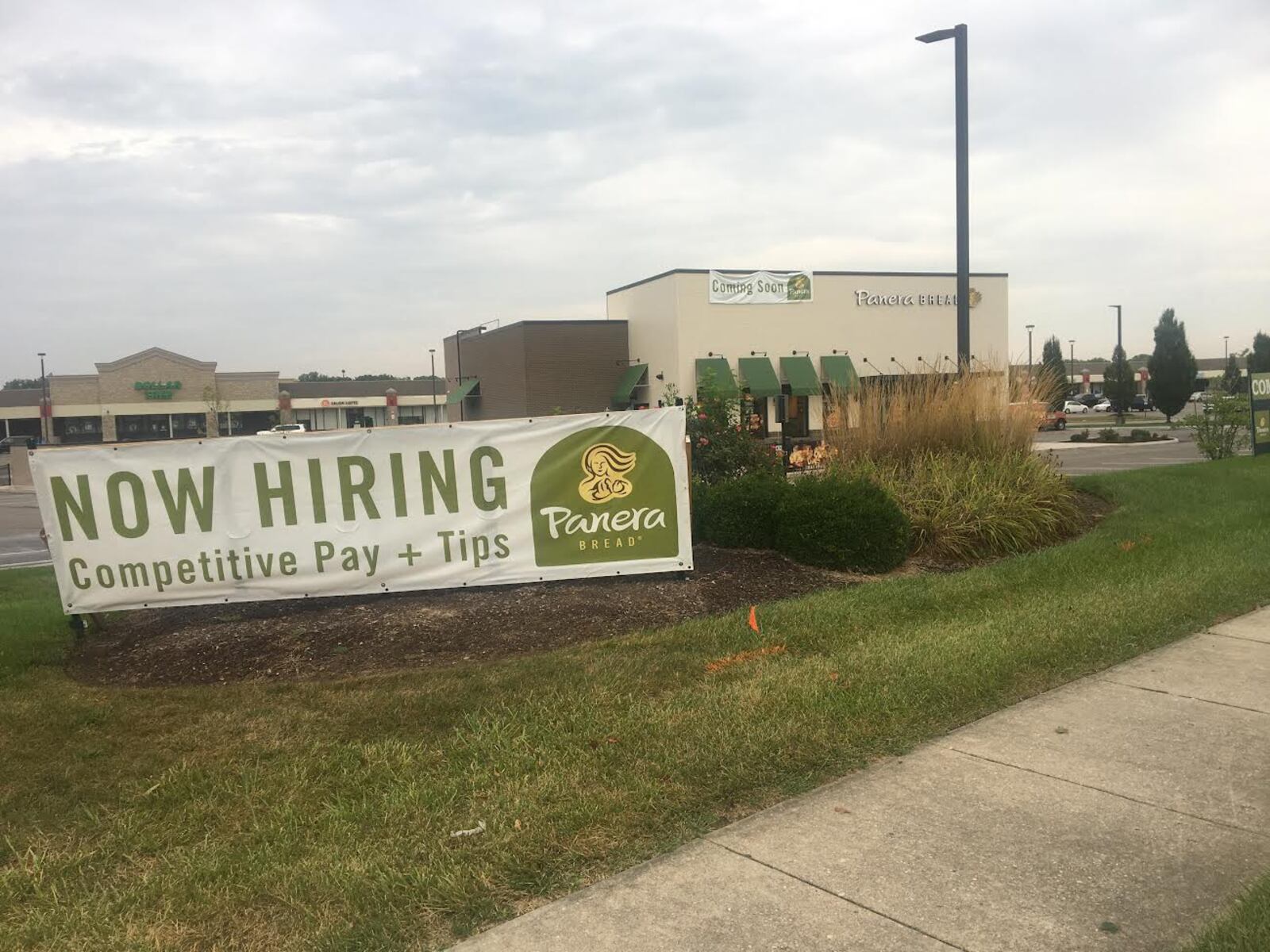 A "Coming Soon" sign hangs from a Panera Bread at the coroner of Lyons Road and Drexel Park Lane near Sam's Club.