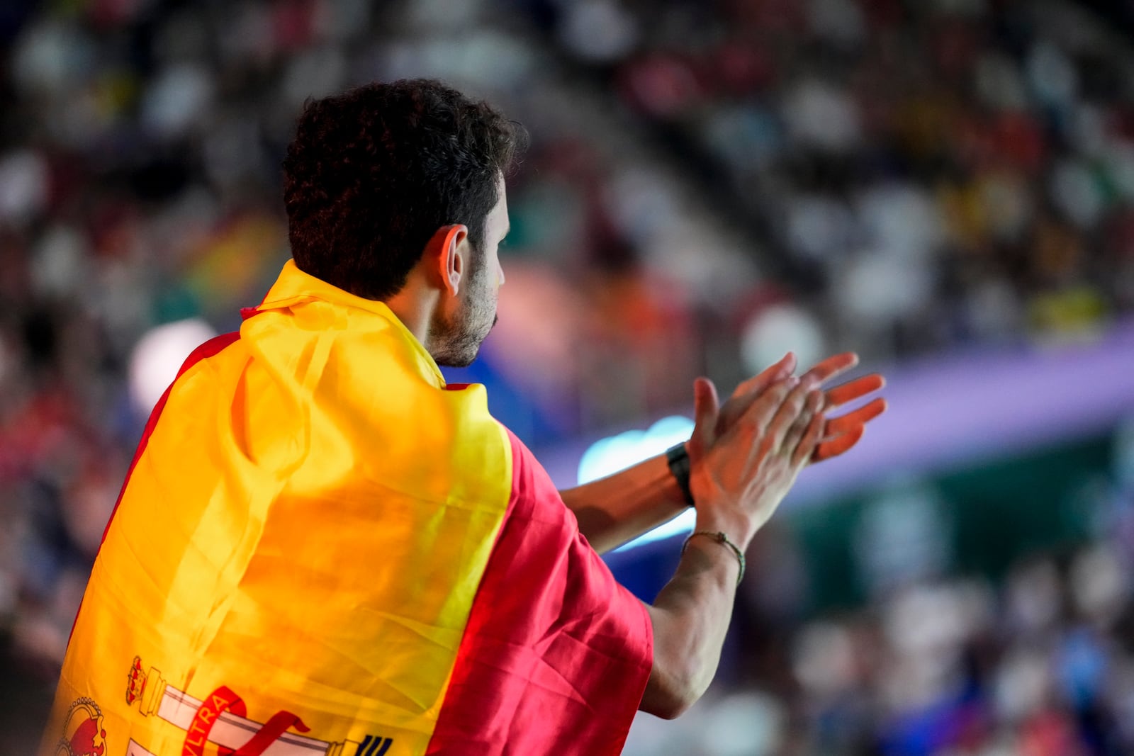 A spectator wrapped with the Spanish flag applauds during the match between Spain's tennis player Rafael Nadal and Netherlands' Botic Van De Zandschulp during a Davis Cup quarterfinal match at Martin Carpena Sports Hall in Malaga, southern Spain, on Tuesday, Nov. 19, 2024. (AP Photo/Manu Fernandez)