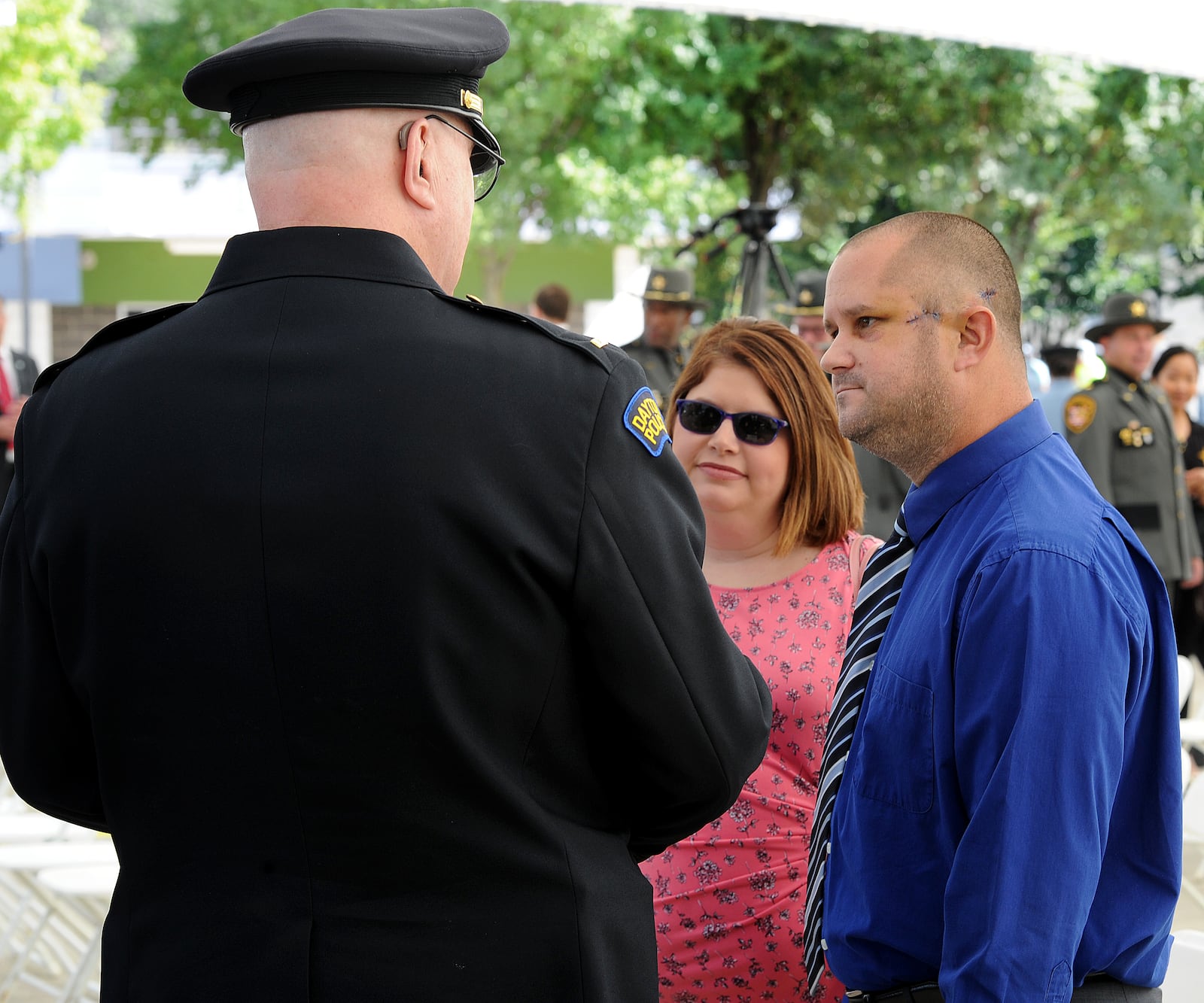 Officer Thadeu Holloway with his wife, Amanda, talks with other officers during the Montgomery County 14th annual Law Enforcement Memorial Ceremony Monday, Sept. 27, 2021. Holloway, an eight-year veteran of the Dayton Police Department, was shot in the left side of his head last Tuesday, Sept. 21, 2021, during a confrontation with a suspect. MARSHALL GORBY\STAFF