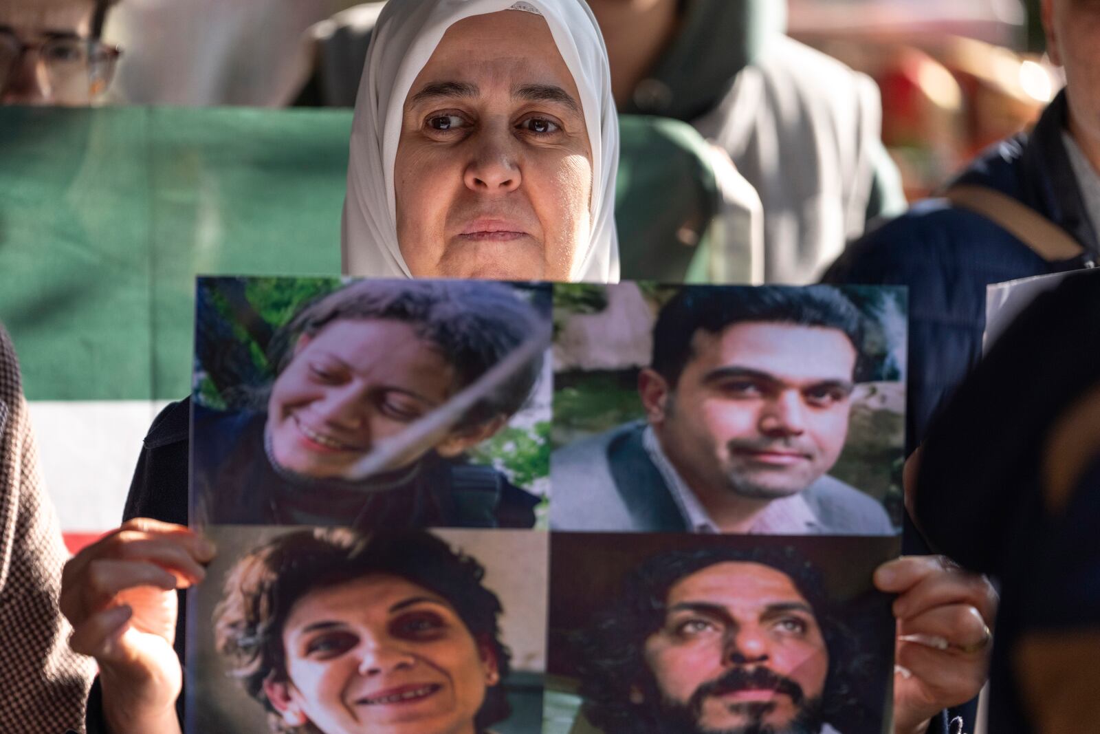 A woman holds photos of four activists who disappeared during the war between opposition forces and Assad regime, at a protest demanding answers to their whereabouts, in Douma, Syria, Wednesday, Jan. 1, 2025. (AP Photo/Mosa'ab Elshamy)