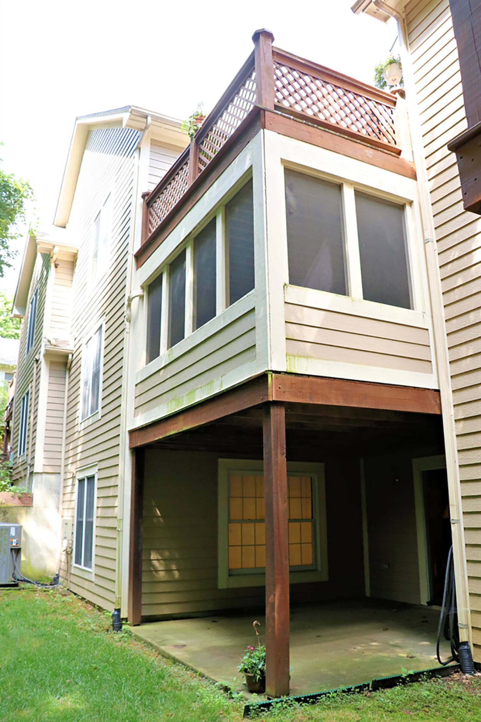 At top, triple patio doors open from the great room to the wooden balcony deck that has views of a tree-lined creek. The deck is above a screen-enclosed porch deck with the same tree-lined creek view. At bottom is a covered concrete patio that opens to rear yard. CONTRIBUTED PHOTO BY KATHY TYLER