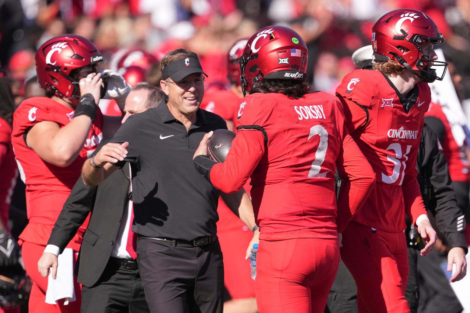 Cincinnati head coach Scott Satterfield, left, and Brendan Sorsby, second from right, embrace after a 24-14 win against Arizona State, Saturday, Oct. 19, 2024, in Cincinnati. (AP Photo/Kareem Elgazzar)