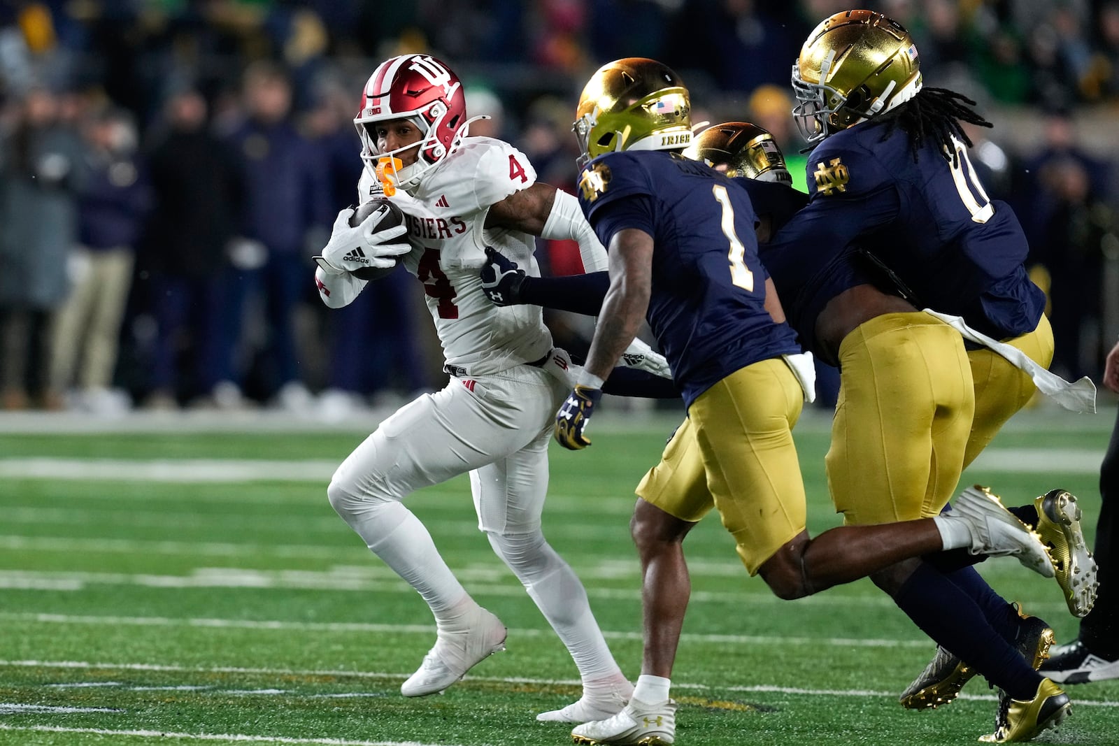 Indiana wide receiver Myles Price (4) tries to outrun Notre Dame safety Jordan Clark (1) safety Xavier Watts (0) during the first half in the first round of the NCAA College Football Playoff, Friday, Dec. 20, 2024, in South Bend, Ind. (AP Photo/Darron Cummings)