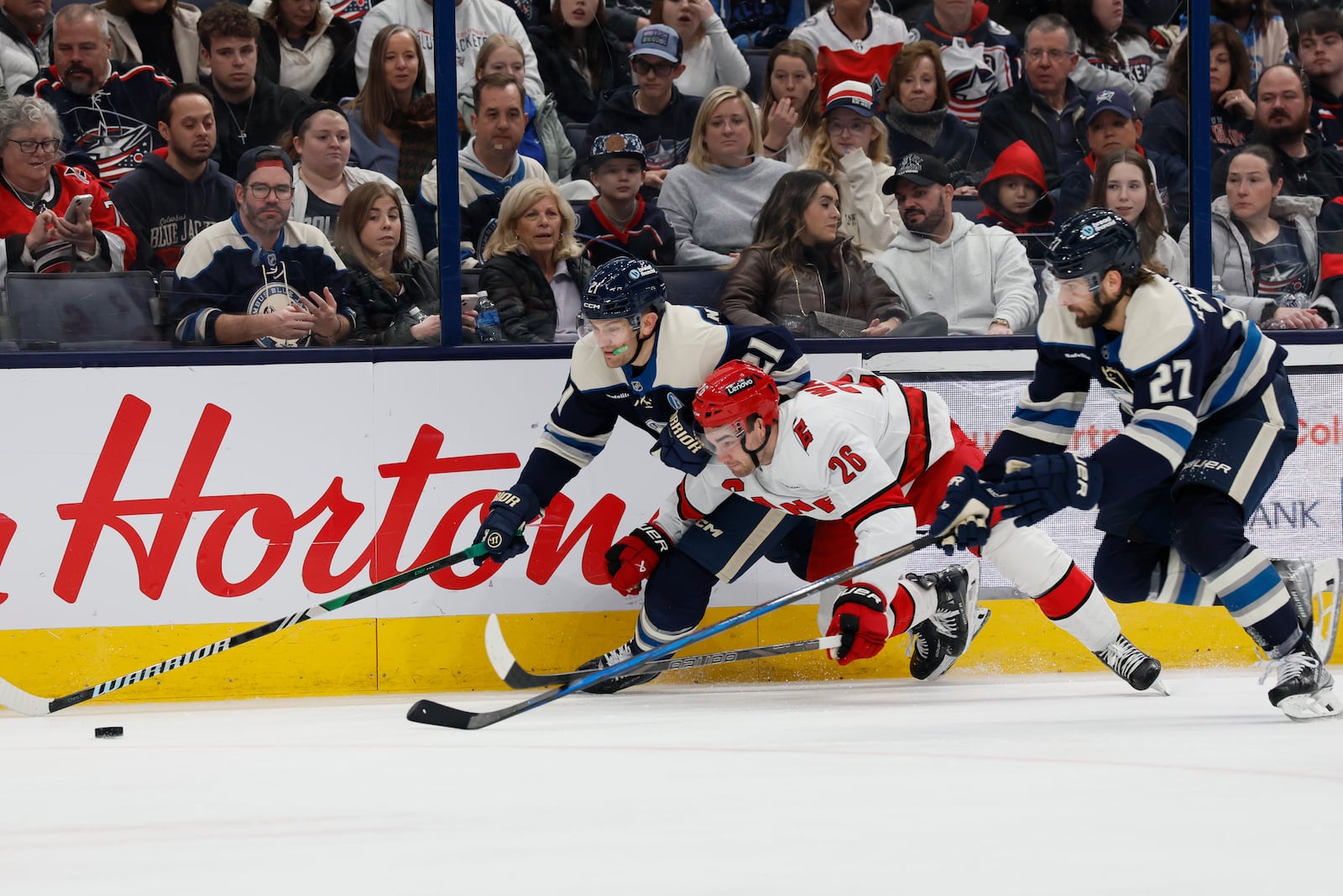 Columbus Blue Jackets' James van Riemsdyk, left, Zachary Aston-Reese, right, and Carolina Hurricanes' Sean Walker chase the puck during the second period of an NHL hockey game, Tuesday, Dec. 31, 2024, in Columbus, Ohio. (AP Photo/Jay LaPrete)