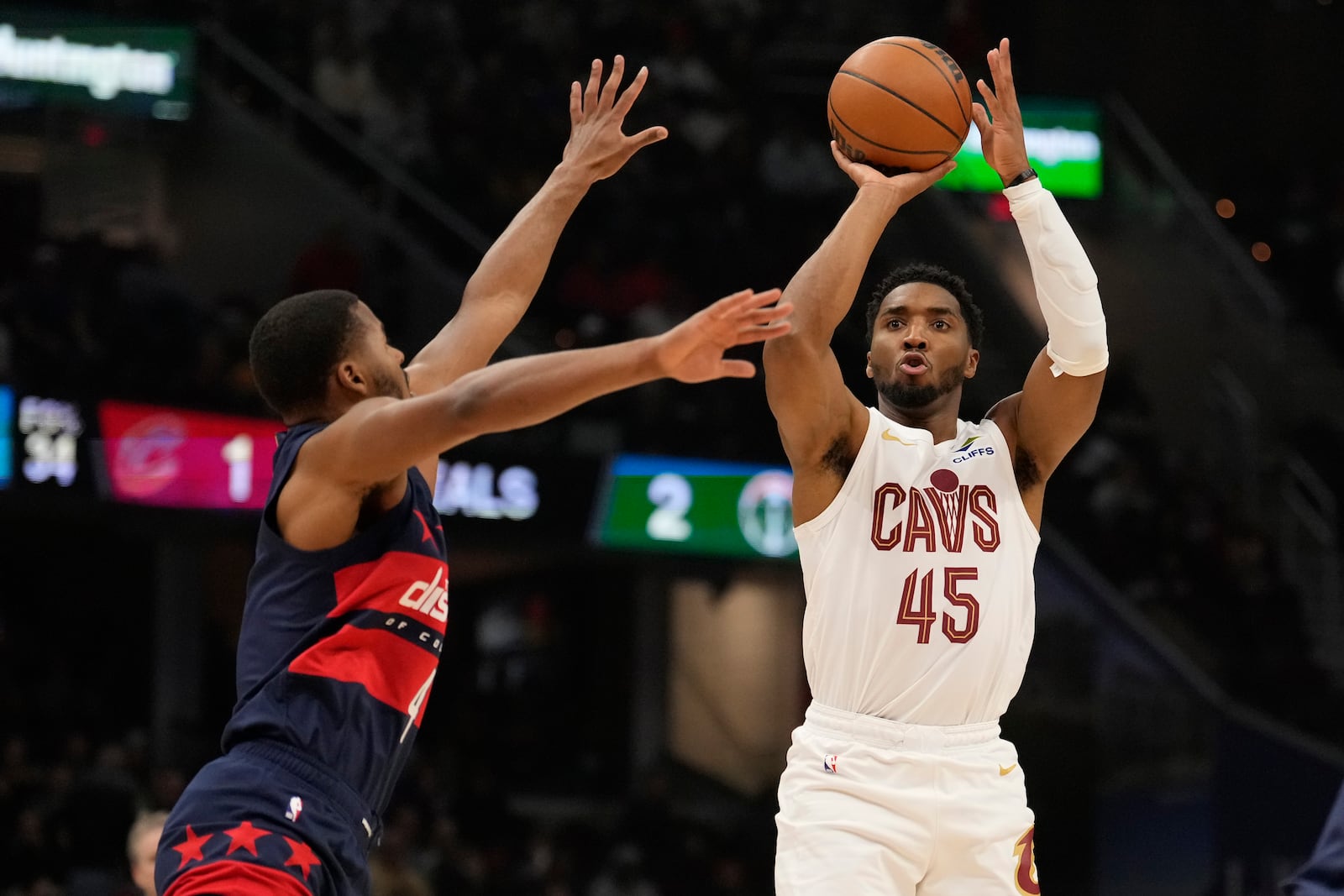 Cleveland Cavaliers guard Donovan Mitchell (45) shoots in front of Washington Wizards guard Jared Butler, left, in the first half of an NBA basketball game, Friday, Dec. 13, 2024, in Cleveland. (AP Photo/Sue Ogrocki)