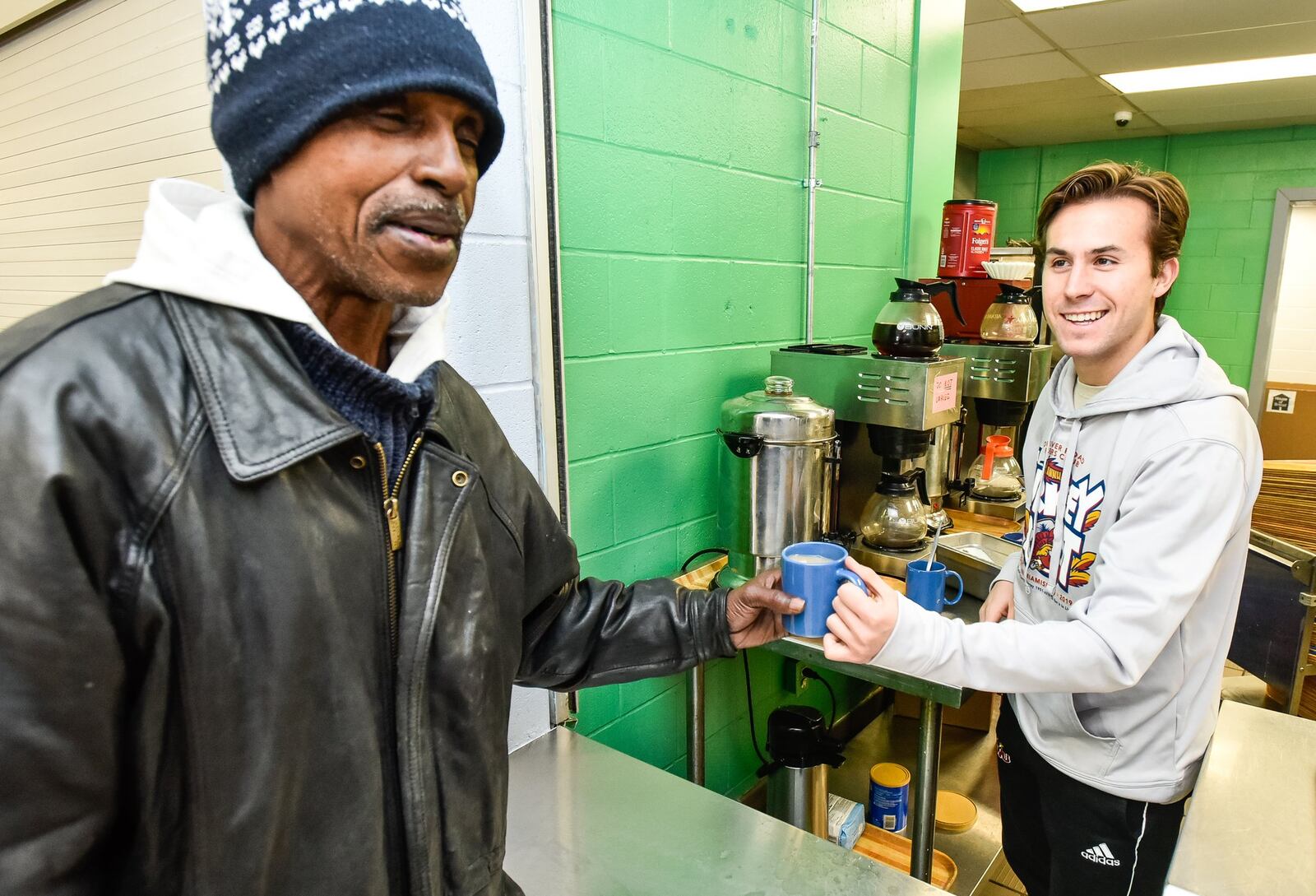 Volunteer Jarrod Ferstl, right, serves coffee to Nicholas Ford at House of Bread non-profit community kitchen Friday, Dec. 20, 2019 in Dayton. NICK GRAHAM/STAFF