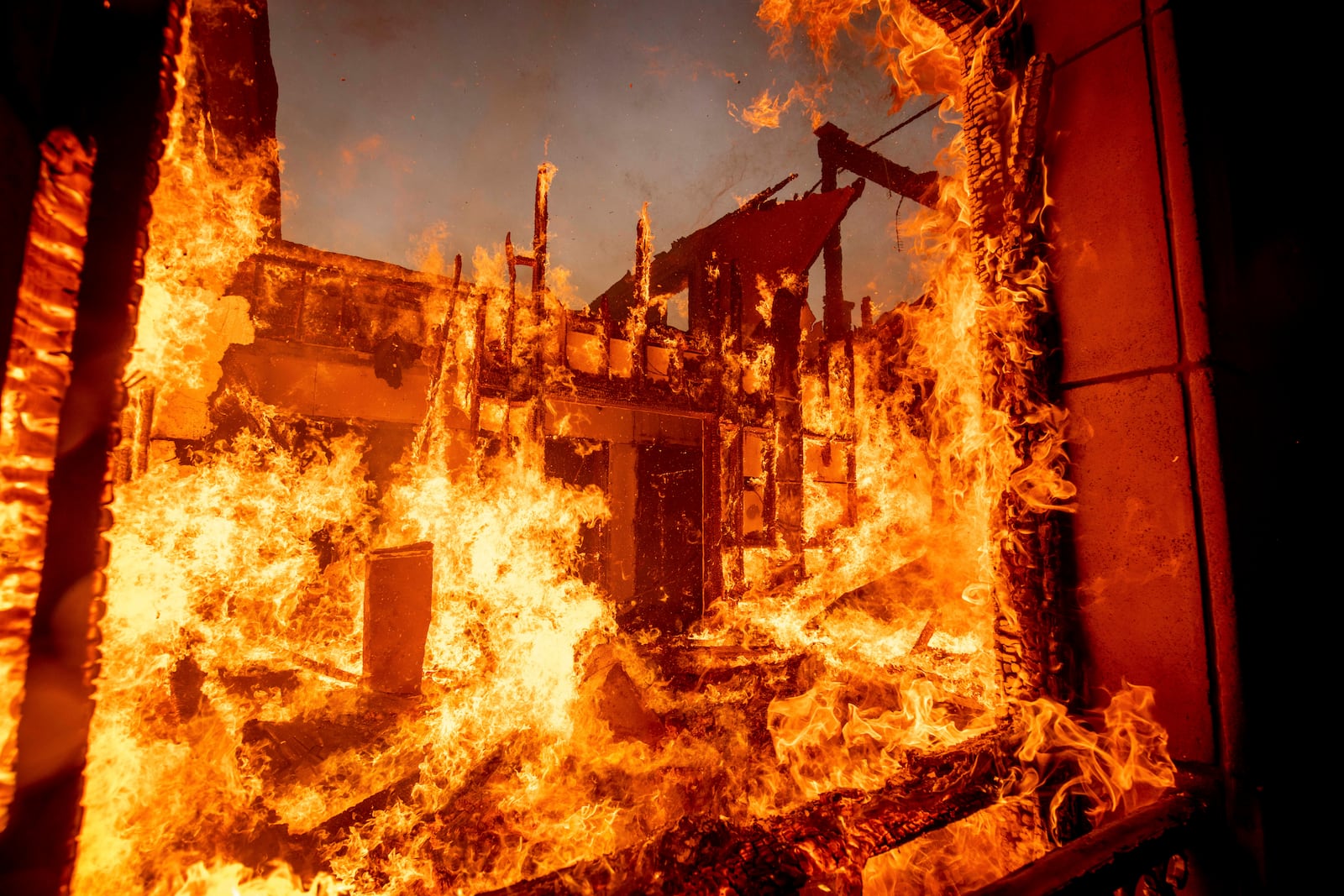 The Palisades Fire burns a residence in the Pacific Palisades neighborhood of Los Angeles, Tuesday, Jan. 7, 2025. (AP Photo/Ethan Swope)