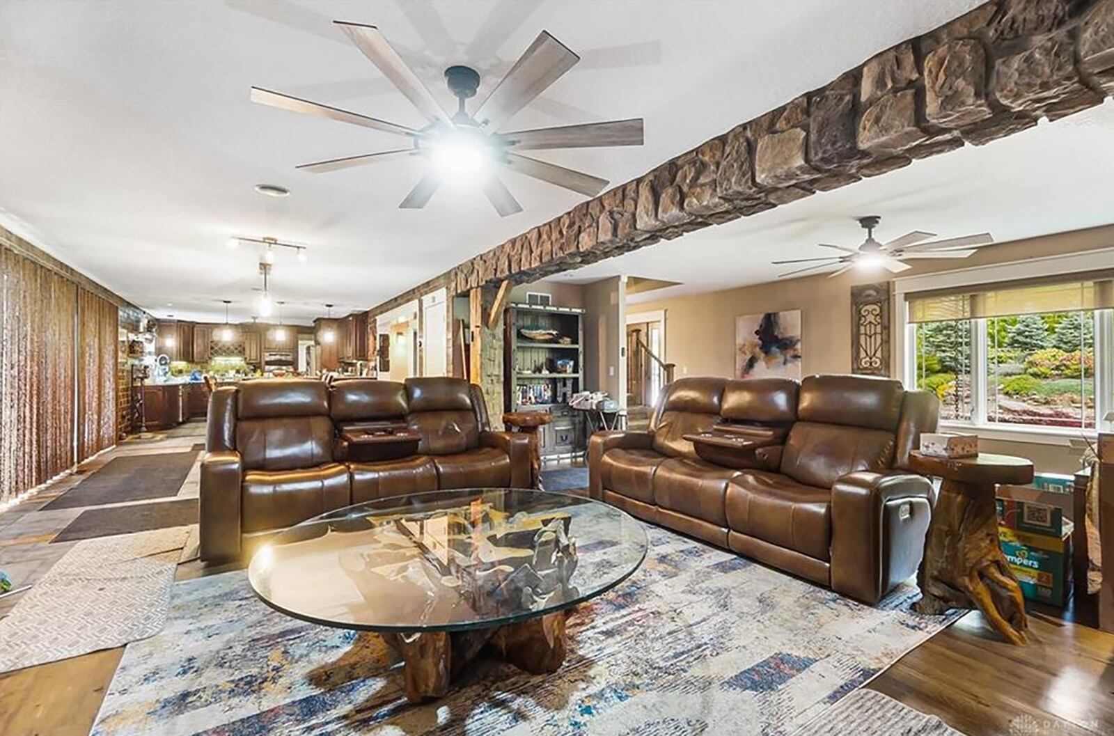 The great room and kitchen are open and feature a stone covered ceiling beam. The great room has a gas fireplace and the kitchen has an integrated dining area.