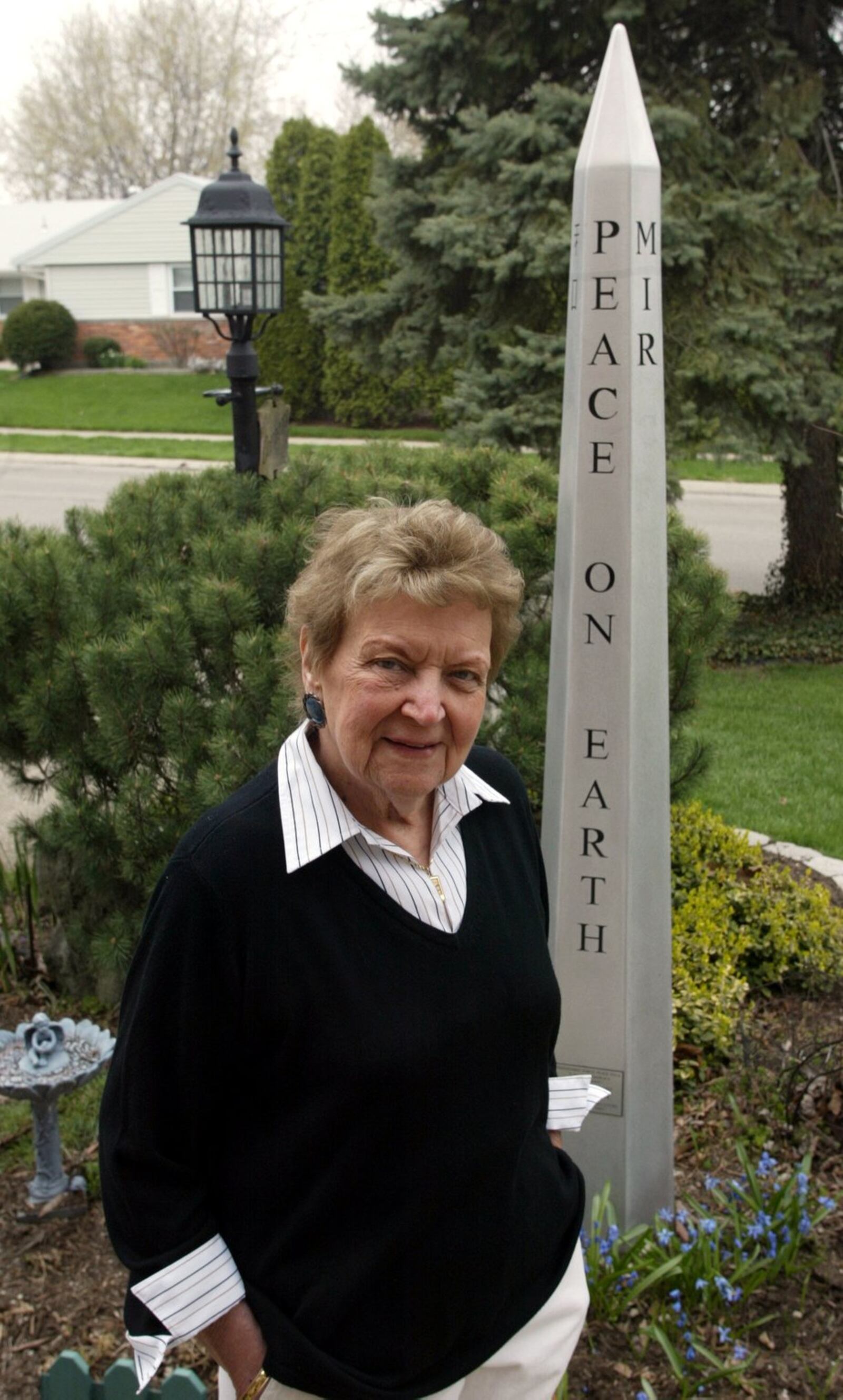 Jeanne Comer, founder of the Dayton Friendship Force, stands before the Peace Pole in her yard. Staff file photo