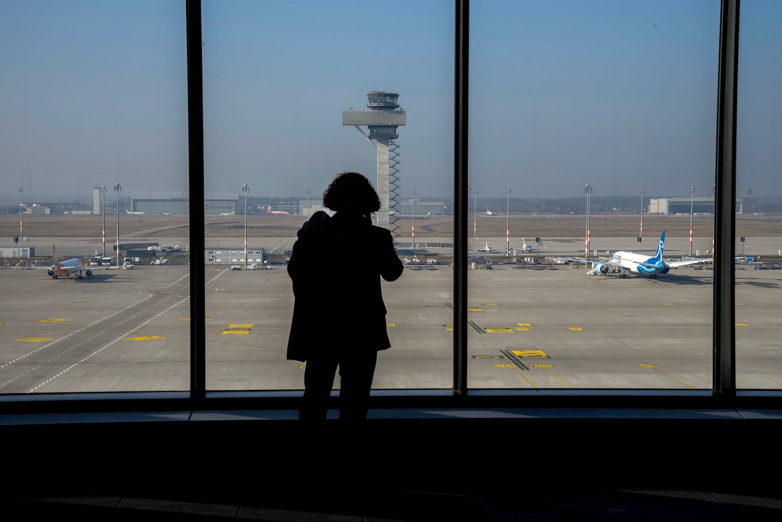 A man watches parked airplanes at the Berlin-Brandenburg airport while all major airports in Germany went on a warning strike, Germany, Monday, March 10, 2025. (AP Photo/Ebrahim Noroozi)