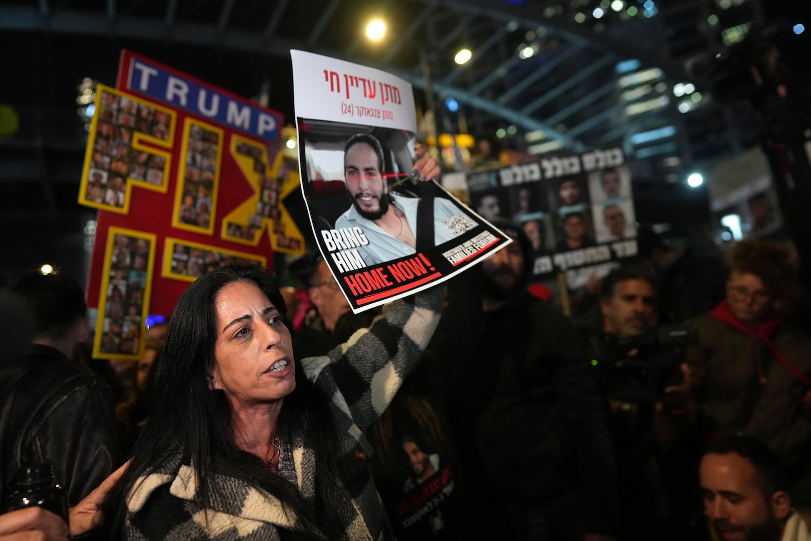 Einav Zangauker holds a poster of her son, Matan, who is held hostage by Hamas in the Gaza Strip, at a protest outside of Israel's Ministry of Defense in Tel Aviv, Israel, Monday, Feb. 10, 2025, after the militant group announced it would delay hostage releases in the Gaza Strip after accusing Israel of violating a fragile ceasefire. (AP Photo/Ohad Zwigenberg)