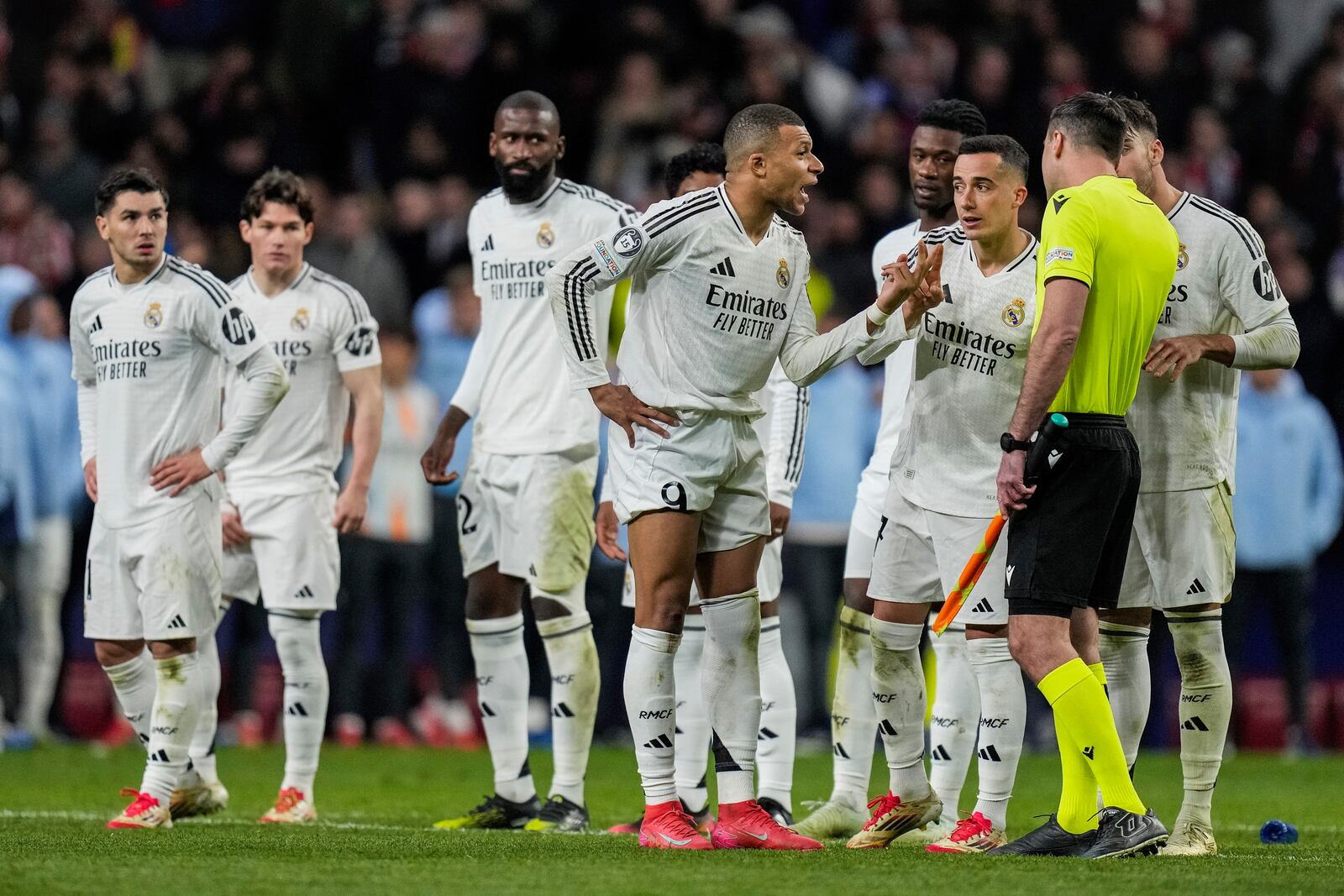 Real Madrid's Kylian Mbappe, center, talks to an assistant referee after a penalty kick by Atletico Madrid's Julian Alvarez during a shootout at the end of the Champions League round of 16, second leg, soccer match between Atletico Madrid and Real Madrid at the Metropolitano stadium in Madrid, Spain, Wednesday, March 12, 2025. (AP Photo/Bernat Armangue)