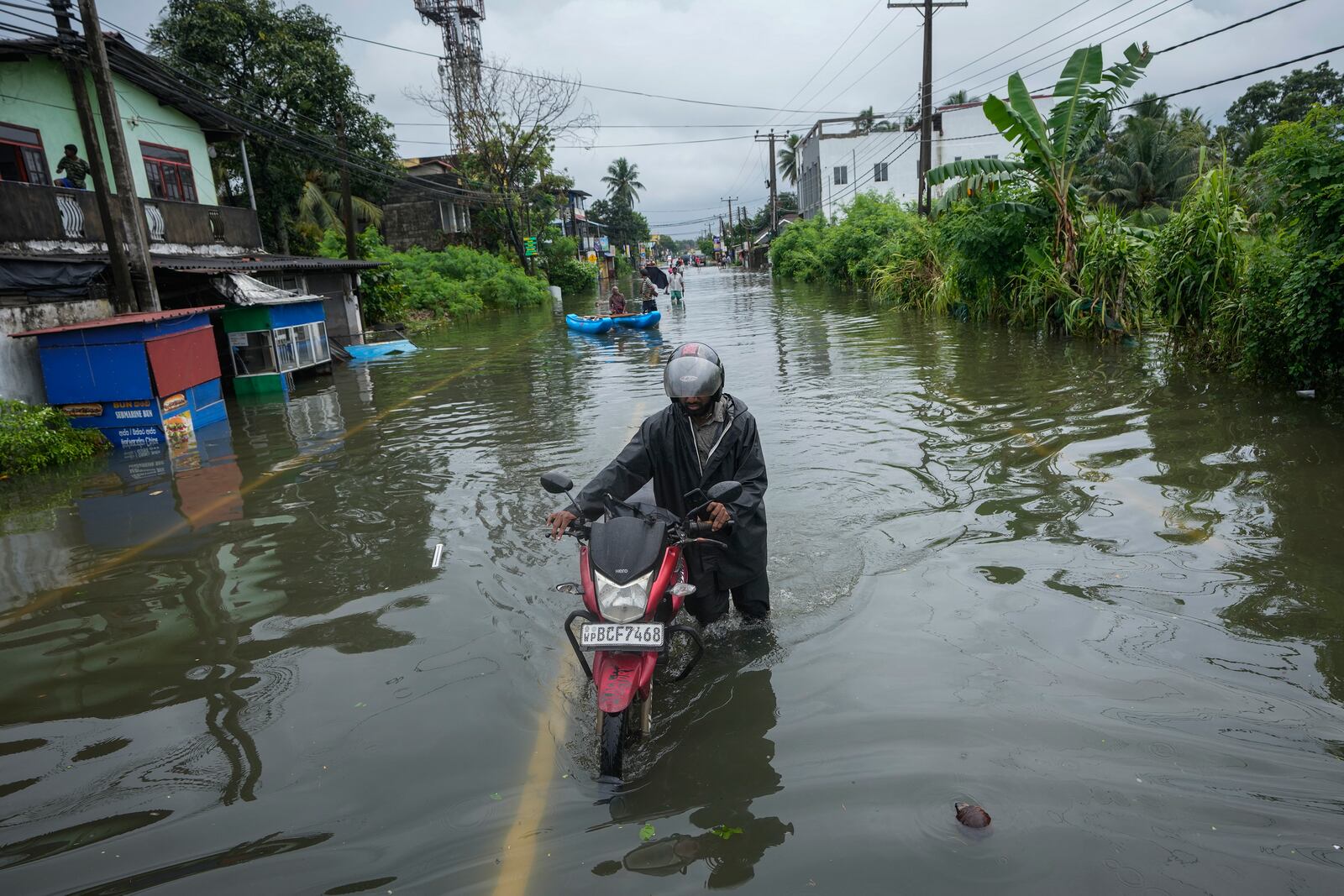 A man pushes his motorbike along a flooded road in Colombo, Sri Lanka, Monday, Oct. 14, 2024. (AP Photo/Eranga Jayawardena)