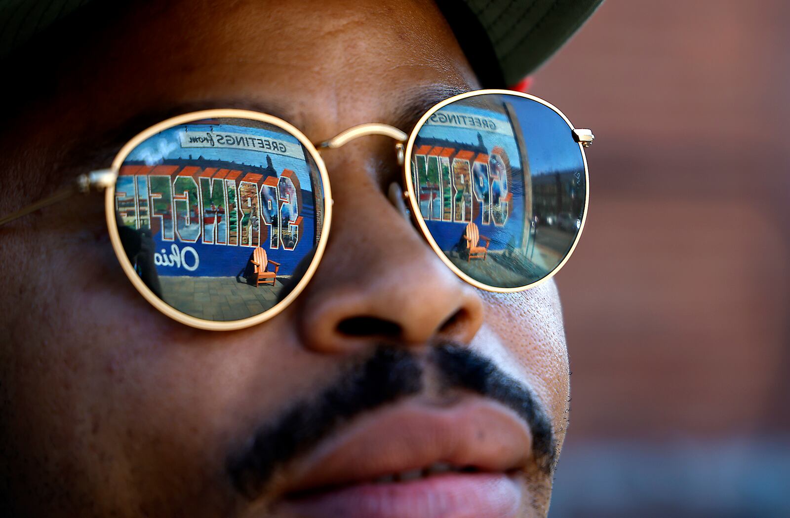 The "Greetings from Springfield" mural is reflected in William Green's sunglasses as he talks about the city and its Haitian population Wednesday, Sept. 11, 2024. BILL LACKEY/STAFF