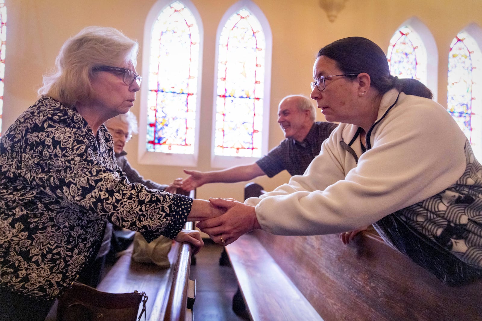 Faithful shake hands at a religious service in the aftermath of the Eaton Fire at Trinity Lutheran Church Sunday, Jan. 12, 2025 in Pasadena, Calif. (AP Photo/Ethan Swope)