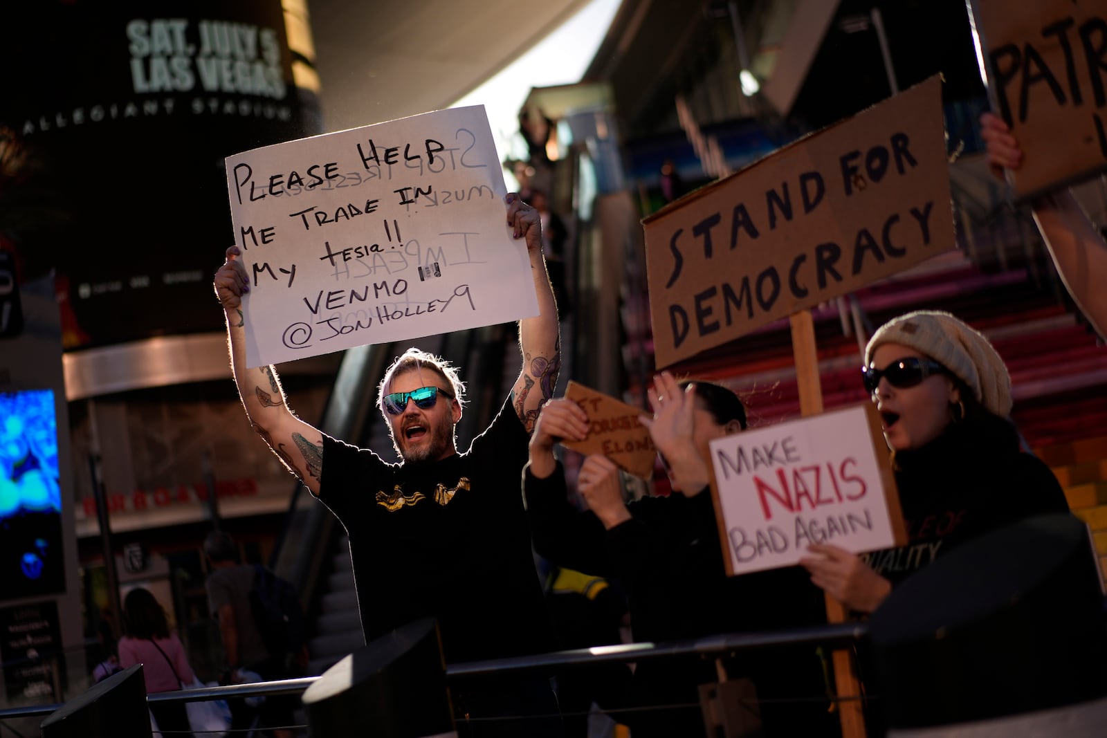 Demonstrators hold signs to protest against the Trump administration along the Las Vegas Strip, Wednesday, Feb. 5, 2025, in Las Vegas. (AP Photo/John Locher)