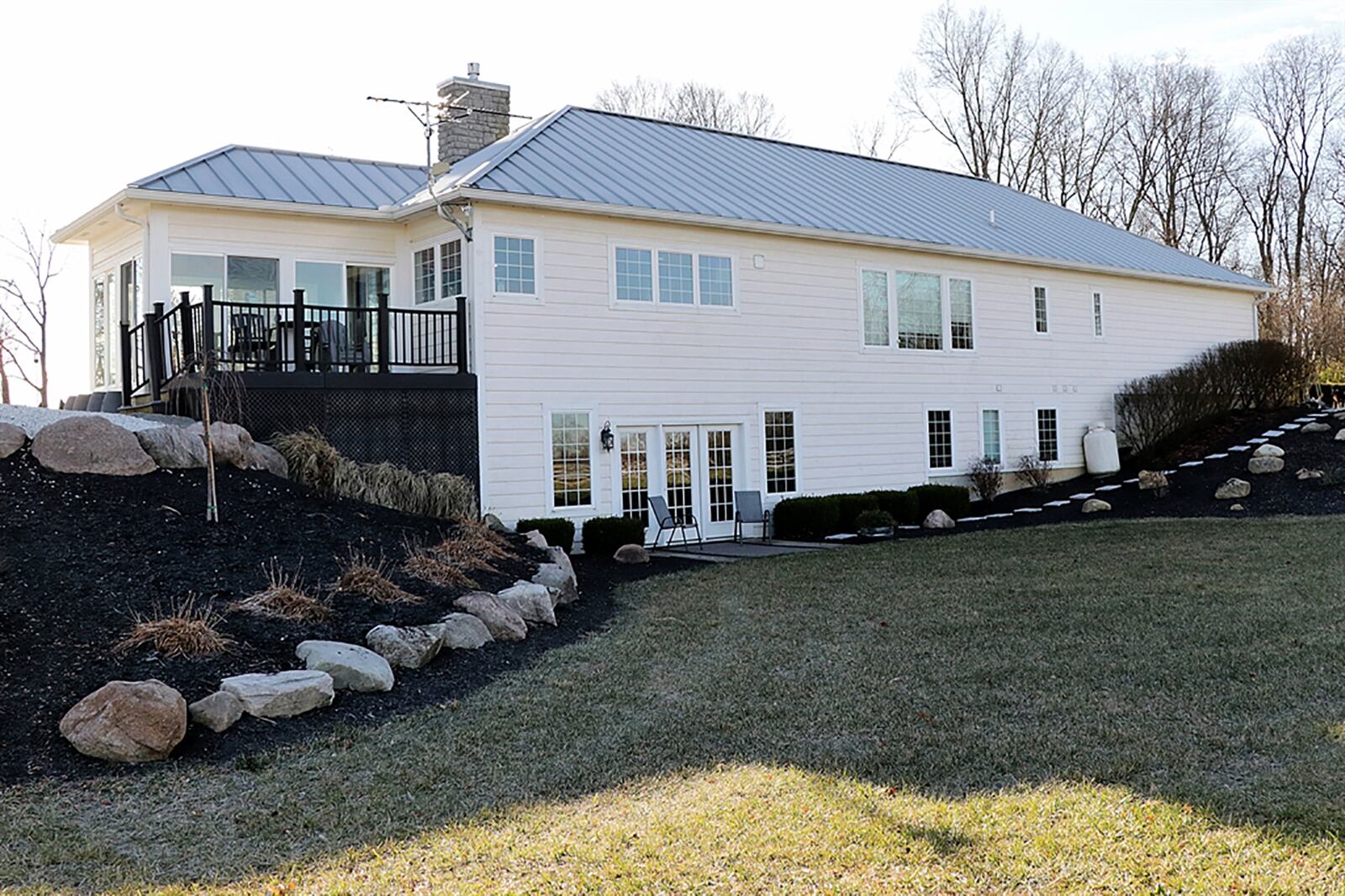 Sliding patio doors open to a 4-season enclosed patio with six sets of sliding patio doors to convert to warmer temperature days. The enclosed porch has a ceiling paddle fan and stone-stamped floor. One set of patio doors open out to a composite deck while another set opens to a sun patio. CONTRIBUTED PHOTO BY KATHY TYLER