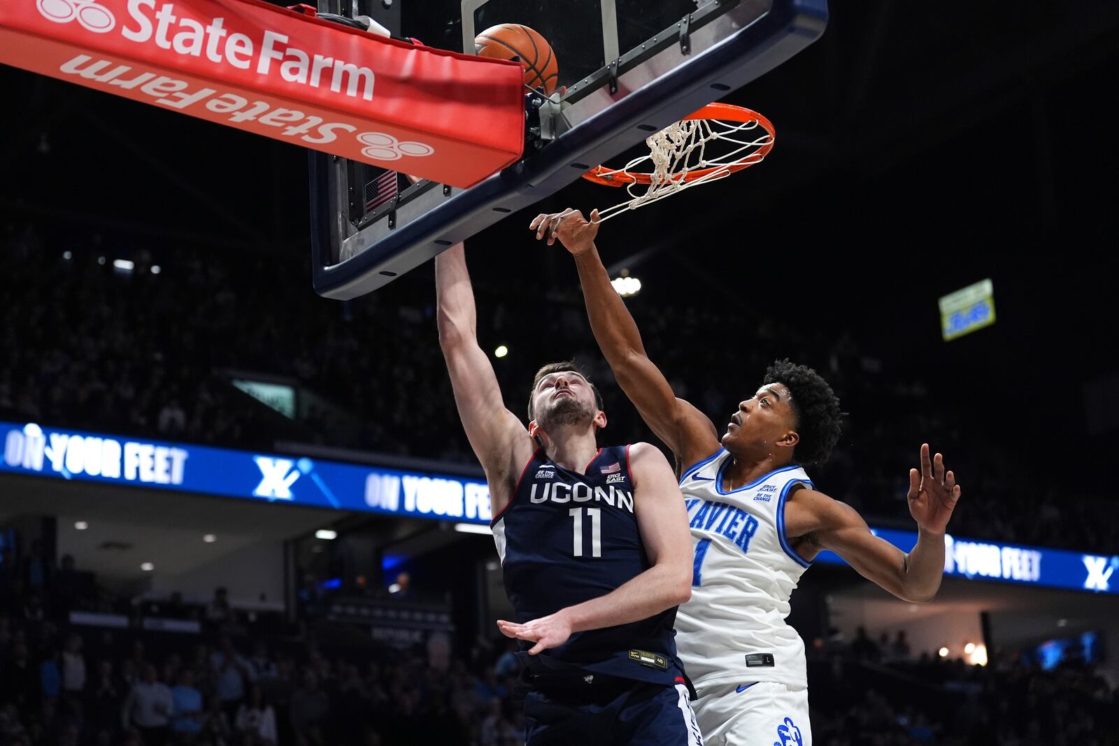 UConn's Alex Karaban scores at the basket as Xavier's Marcus Foster defends during the first half of an NCAA college basketball game, Saturday, Jan. 25, 2025, Cincinnati. (AP Photo/Kareem Elgazzar)