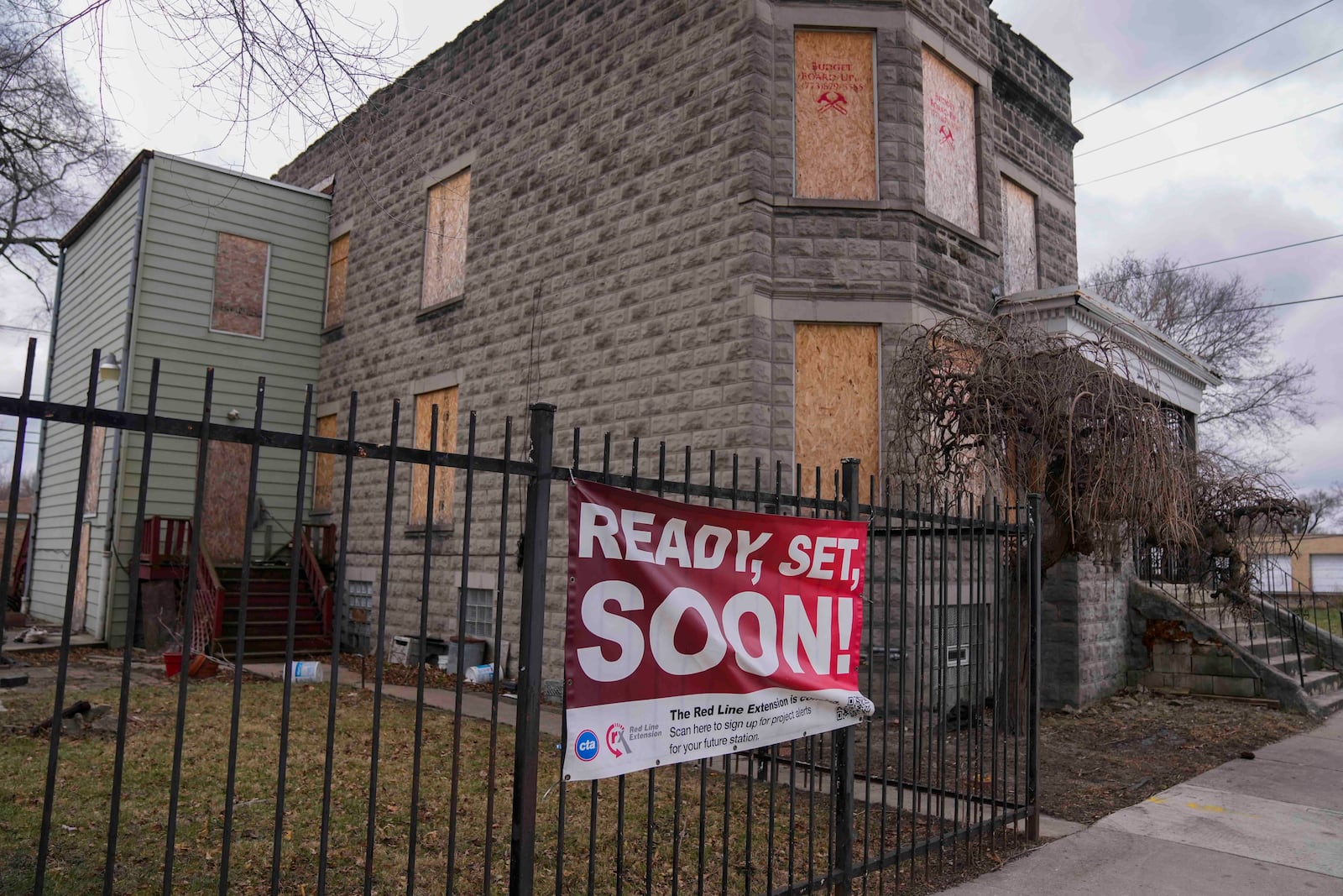 A sign reads "Ready, Set, Soon!" on a boarded-up property set for demolition to make room for a new train station where the Chicago Transit Authority plans to expand the Red Line train route on West 111th Street, Wednesday, Dec. 11, 2024, in the Roseland neighborhood of Chicago. (AP Photo/Erin Hooley)