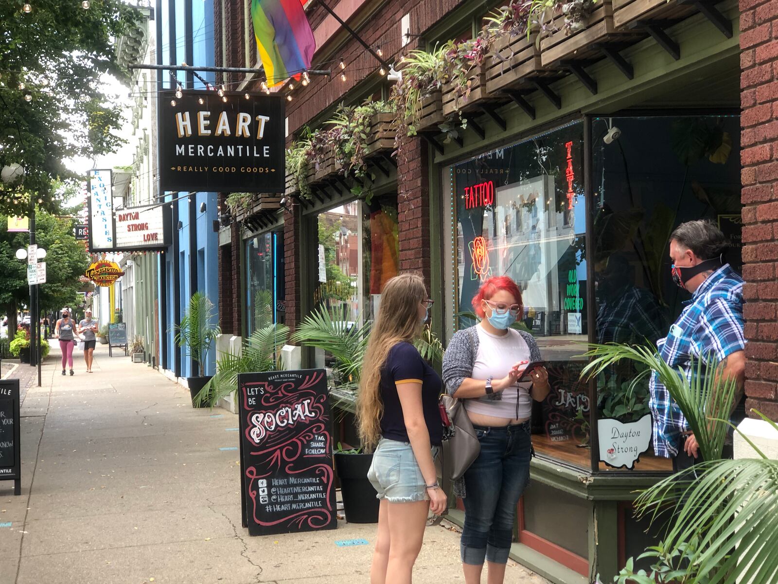 James Collins, owner of Gem City Tattoo Club, talks with customers outside the shop on Saturday, Aug. 1. CORNELIUS FROLIK / STAFF